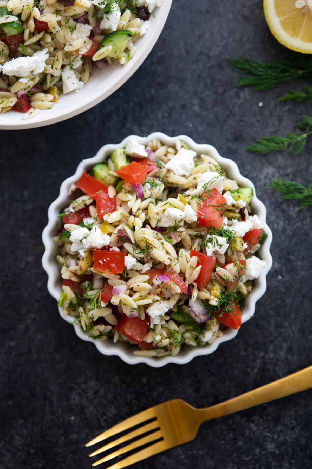 Overhead shot of Mediterranean orzo salad on a black backdrop.