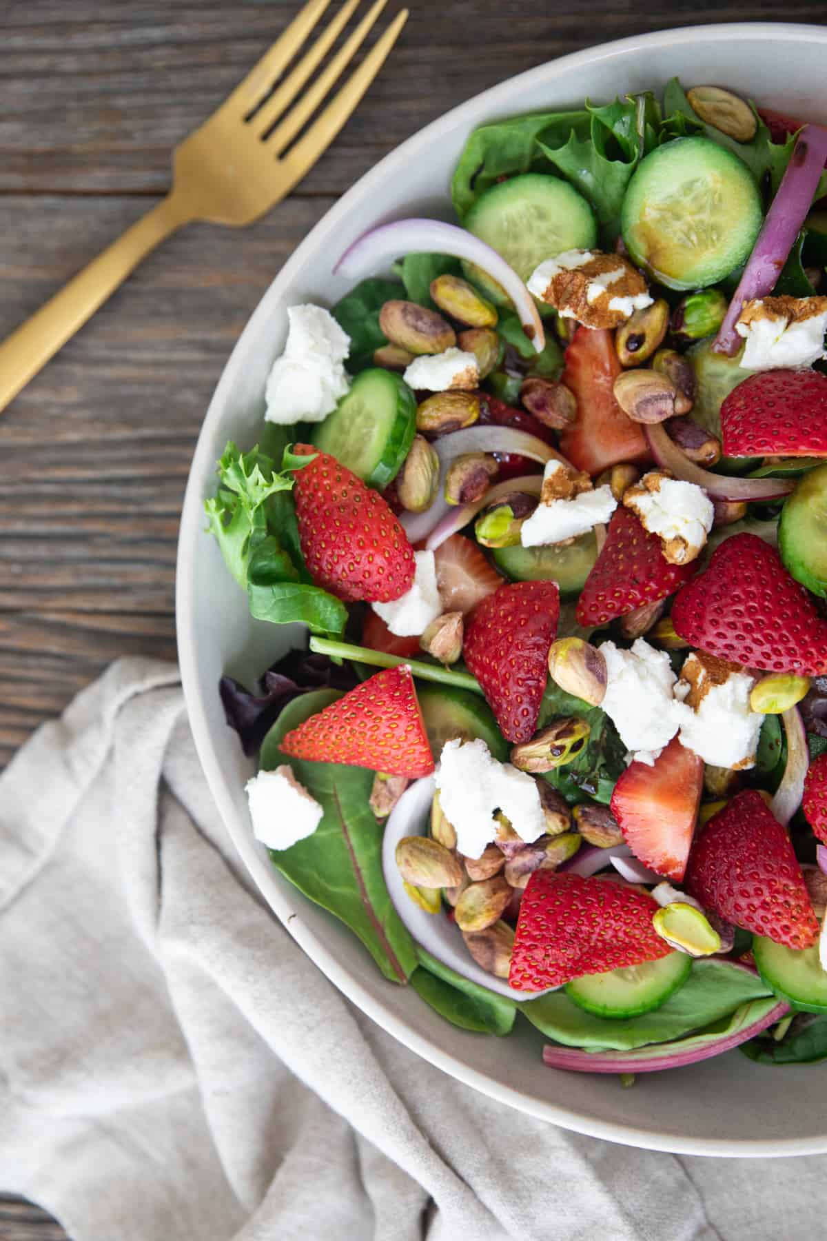 Close up overhead shot of strawberry salad with goat cheese and pistachios. 
