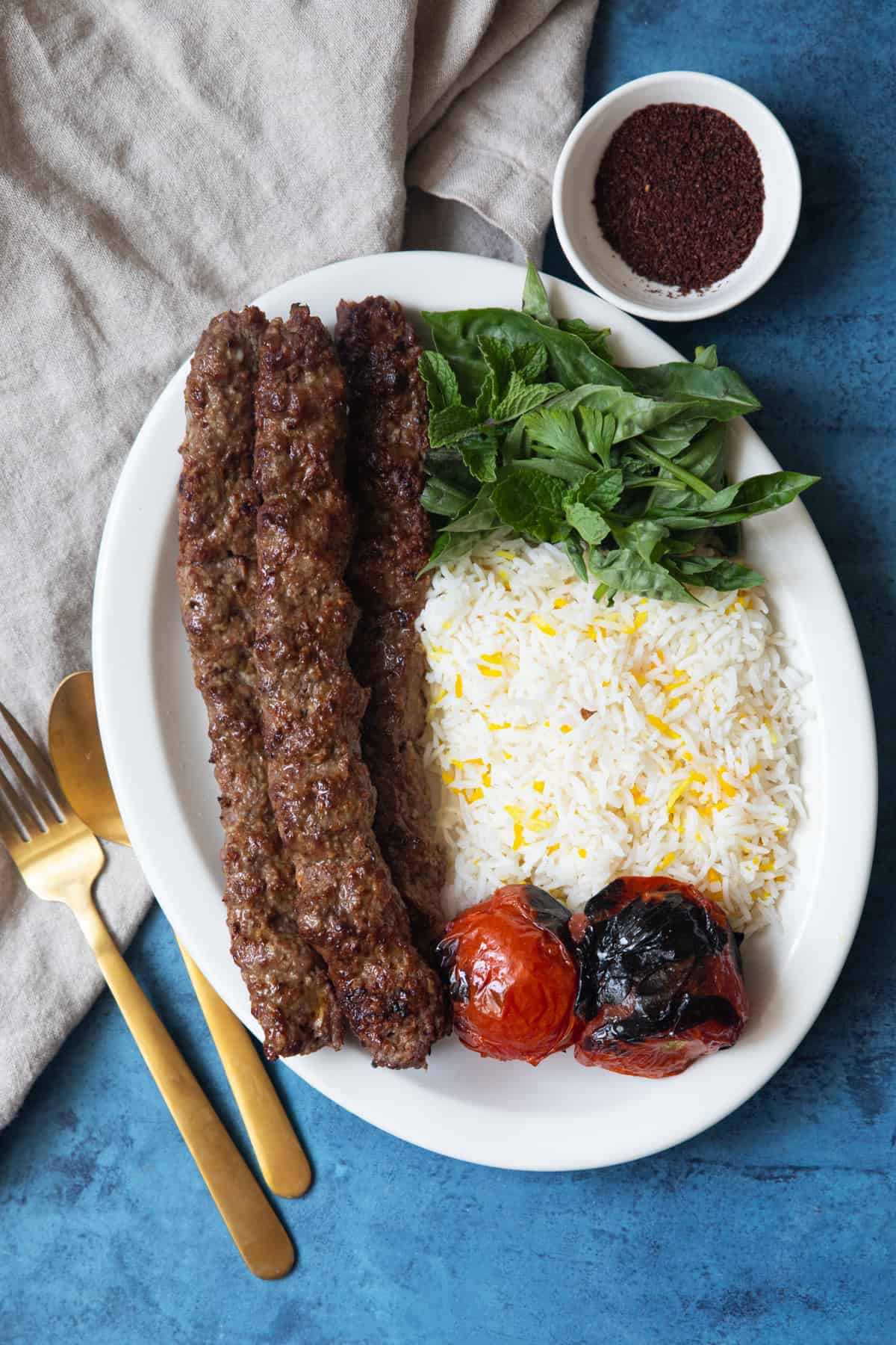 Overhead koobideh kabob with rice, sumac and tomatoes. 