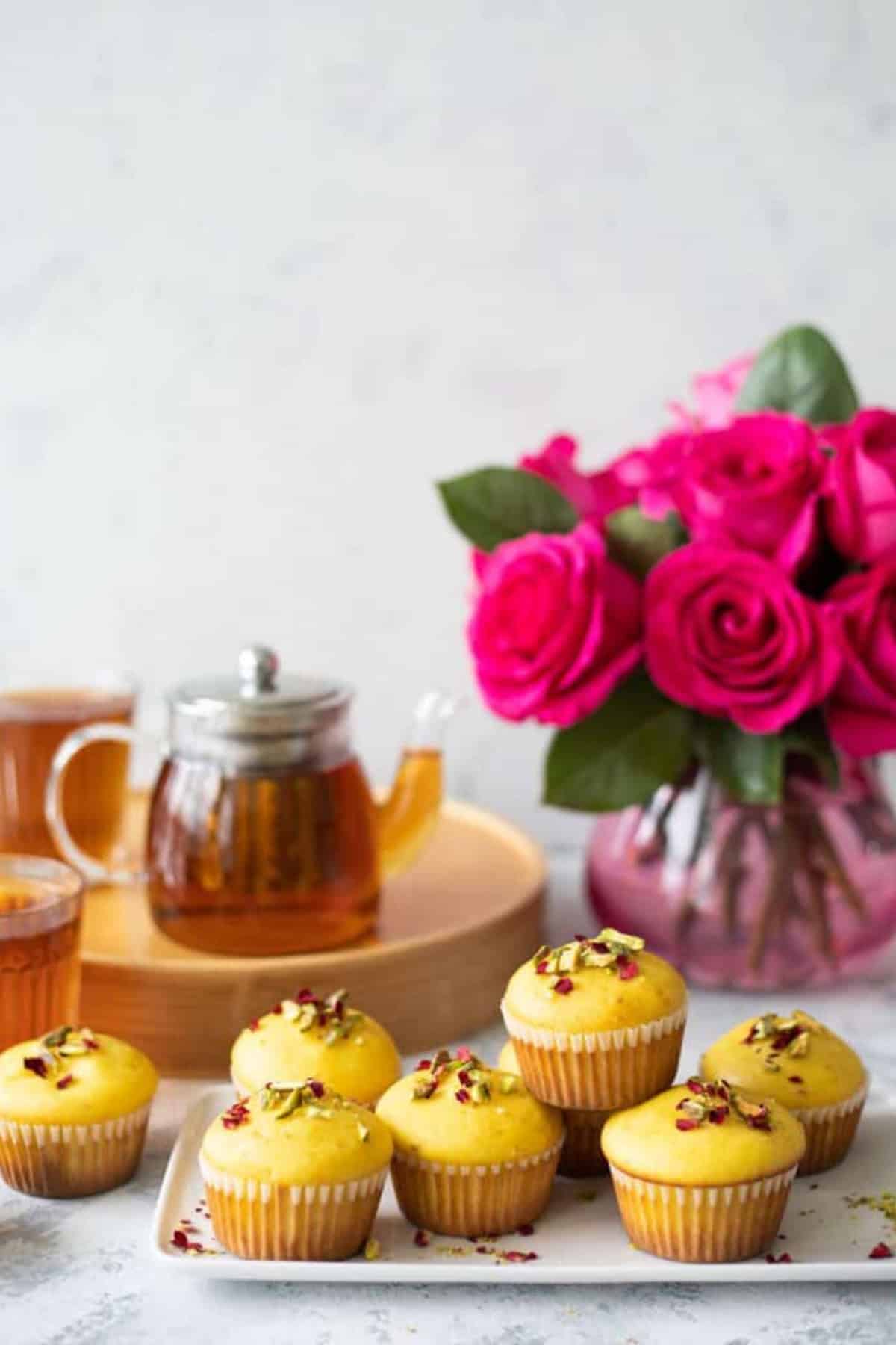 Persian love muffins on a plate with a vase of flowers.
