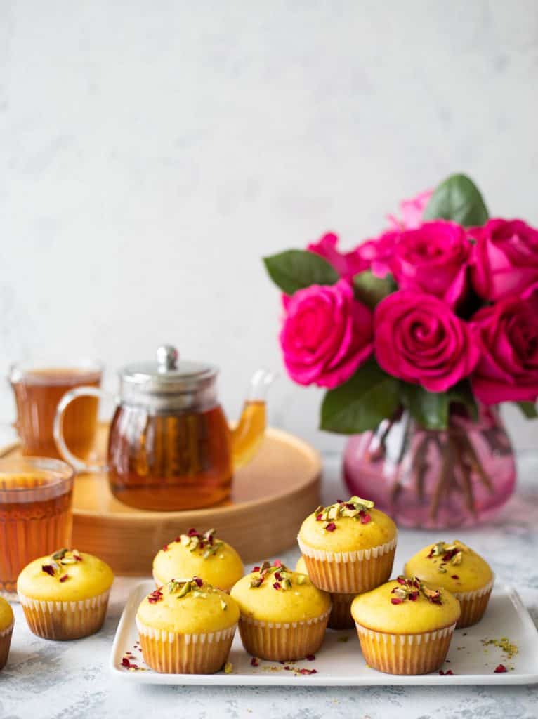 Persian love muffins on a plate with a vase of flowers. 