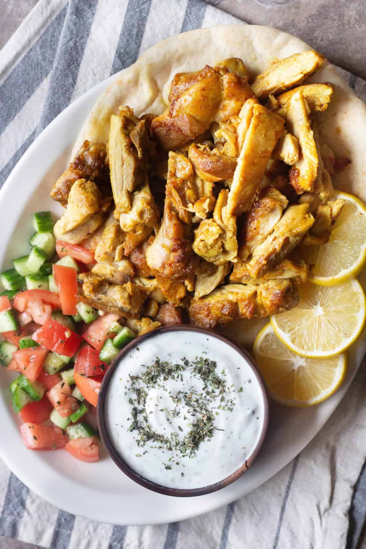 A platter of chicken shawarma with salad, yogurt sauce and lemon with fresh pita bread.
This is a Middle Eastern street food that's packed with flavor thanks to the special spice mixture that brings it all together.