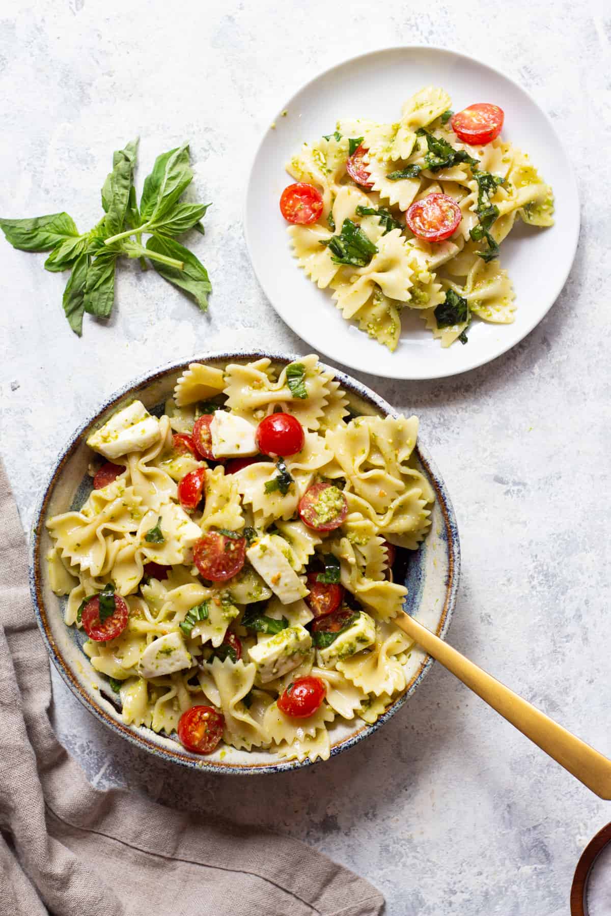 Caprese pasta salad in a bowl on a white background. 