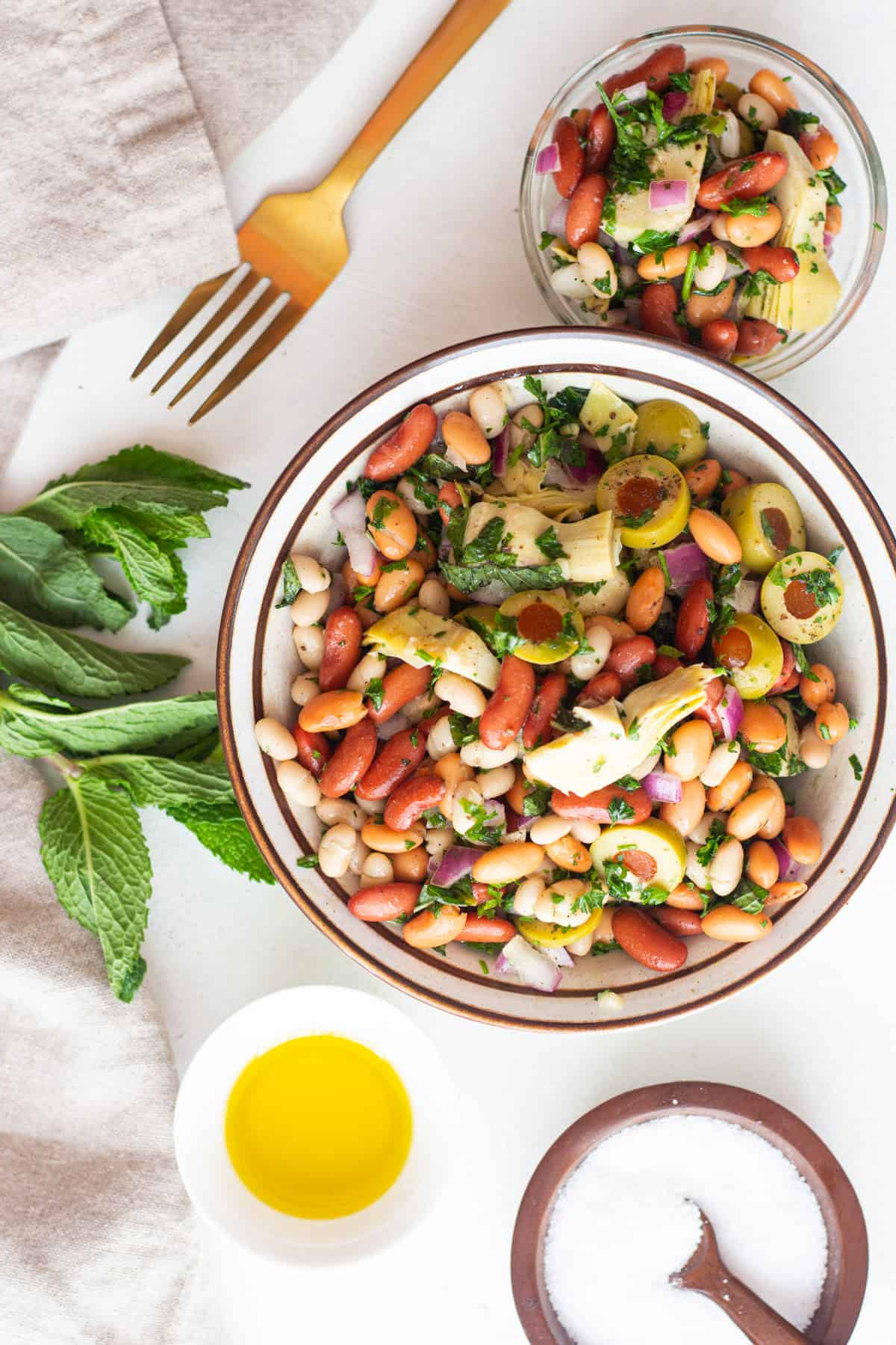 Two bowls of Mediterranean bean salad with mint and olive oil.