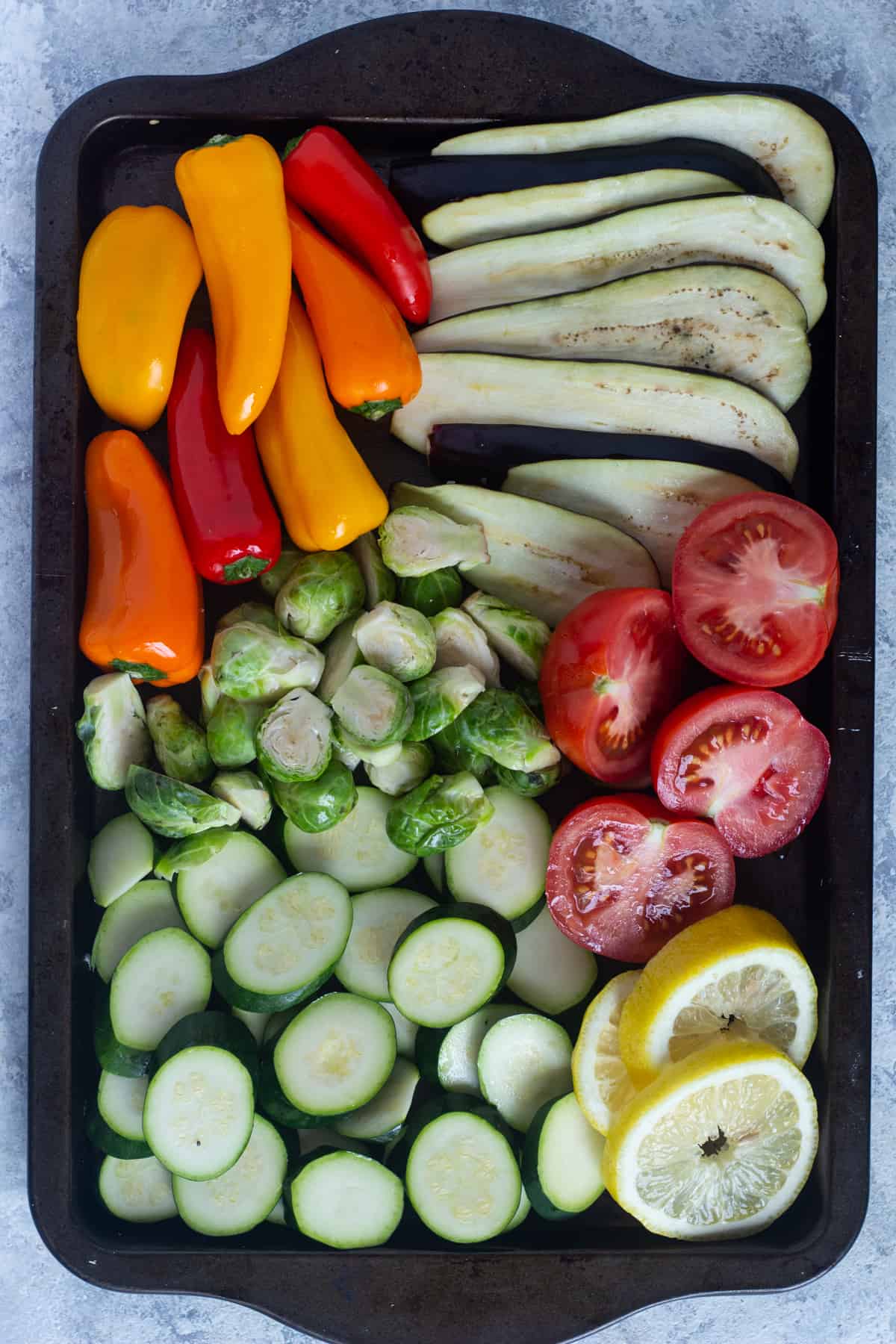 Cut the vegetables into slices and place them on a baking sheet. Drizzle with olive oil.