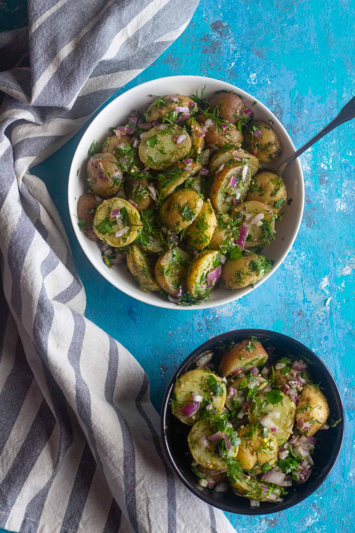 Healthy potato salad in two bowls with a napkin and a spoon