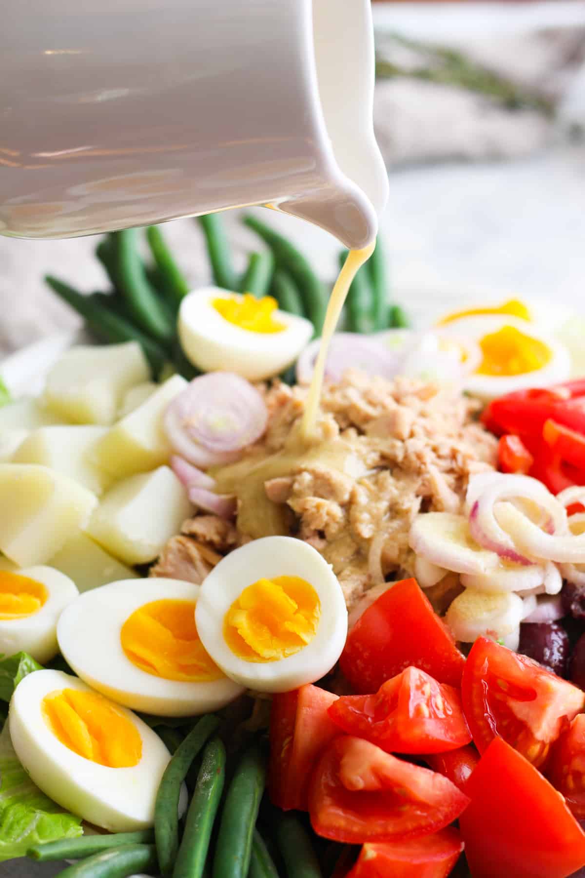 Dijon dressing poured on nicoise salad.