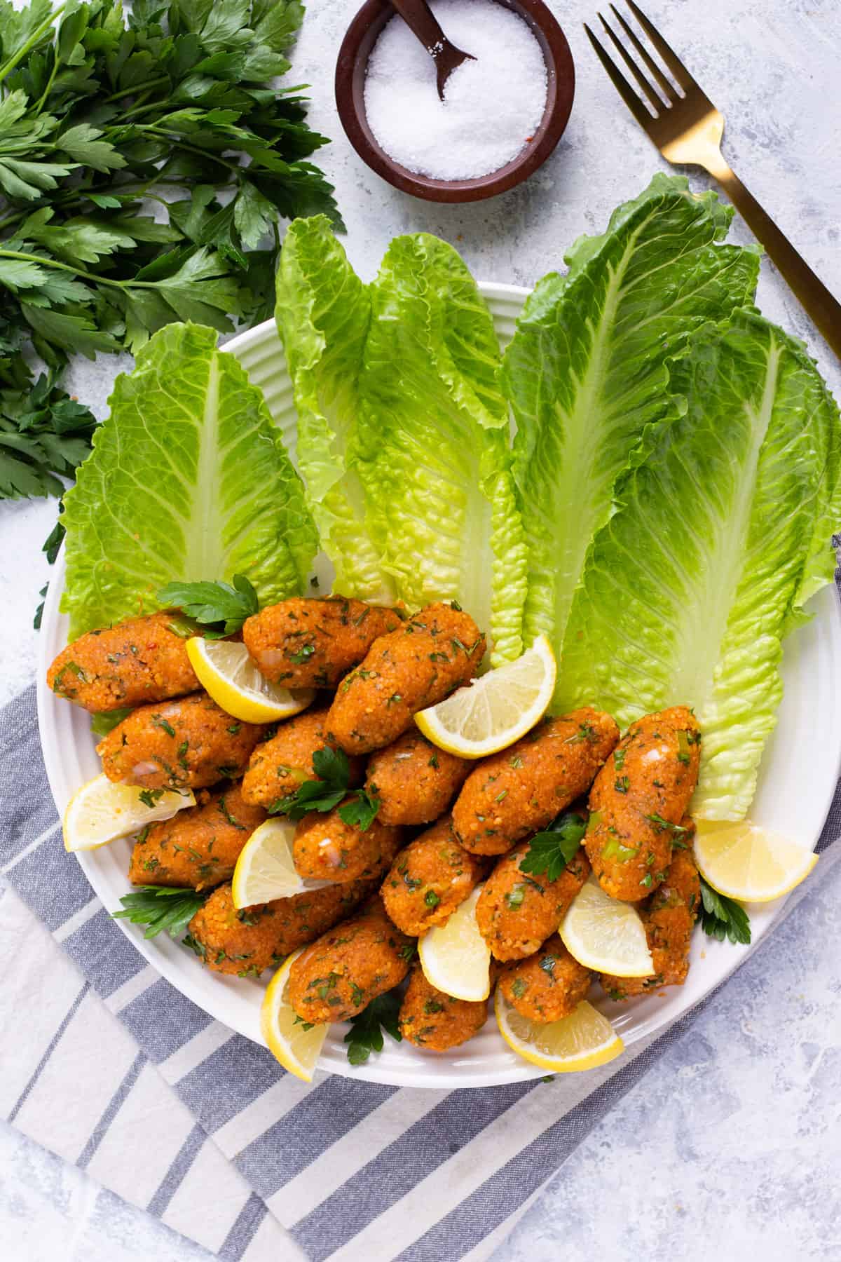 Turkish vegan red lentil balls in a platter with fresh lettuce and lemon slices. 