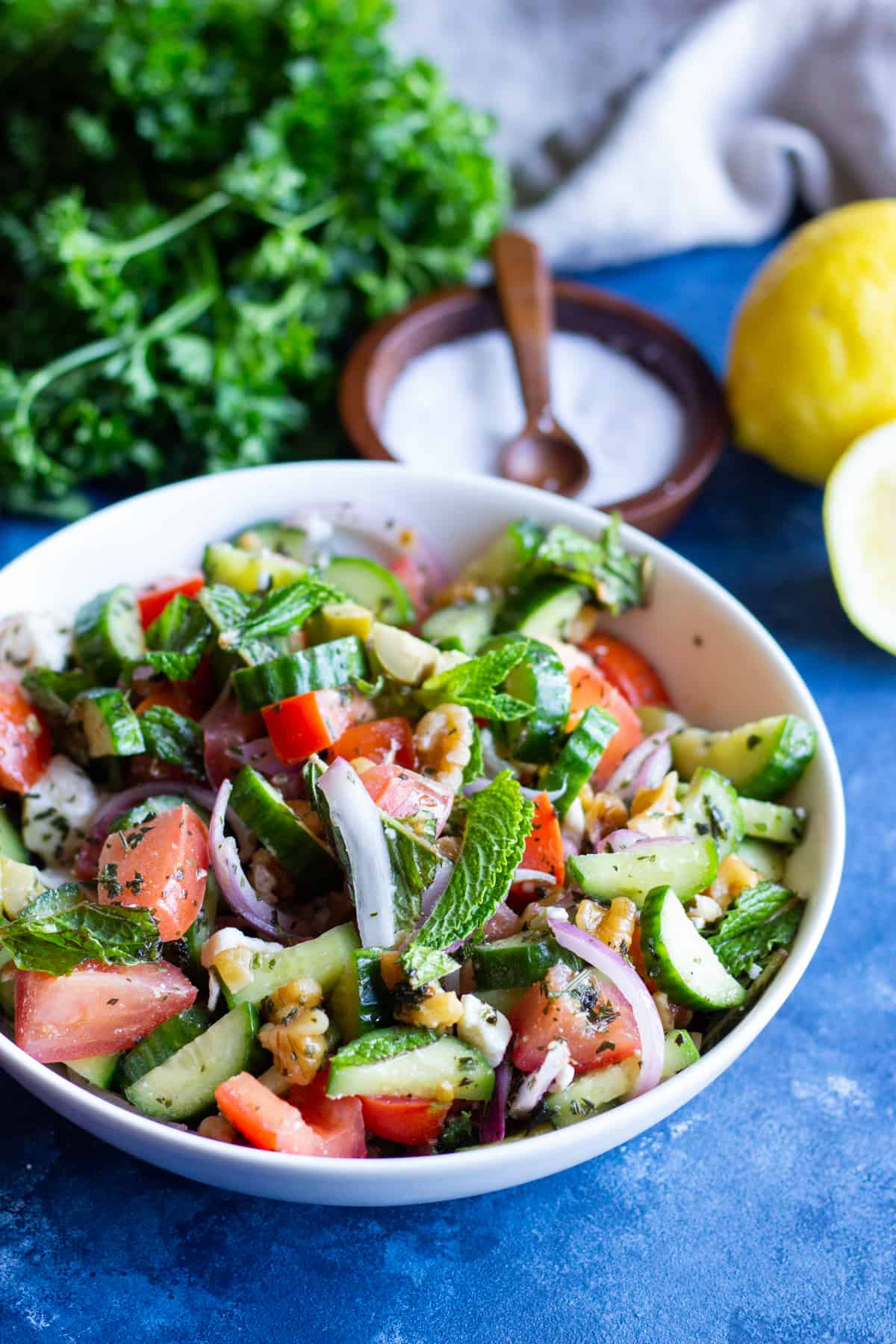 A bowl of tomato feta salad with fresh mints and salt and lemon.