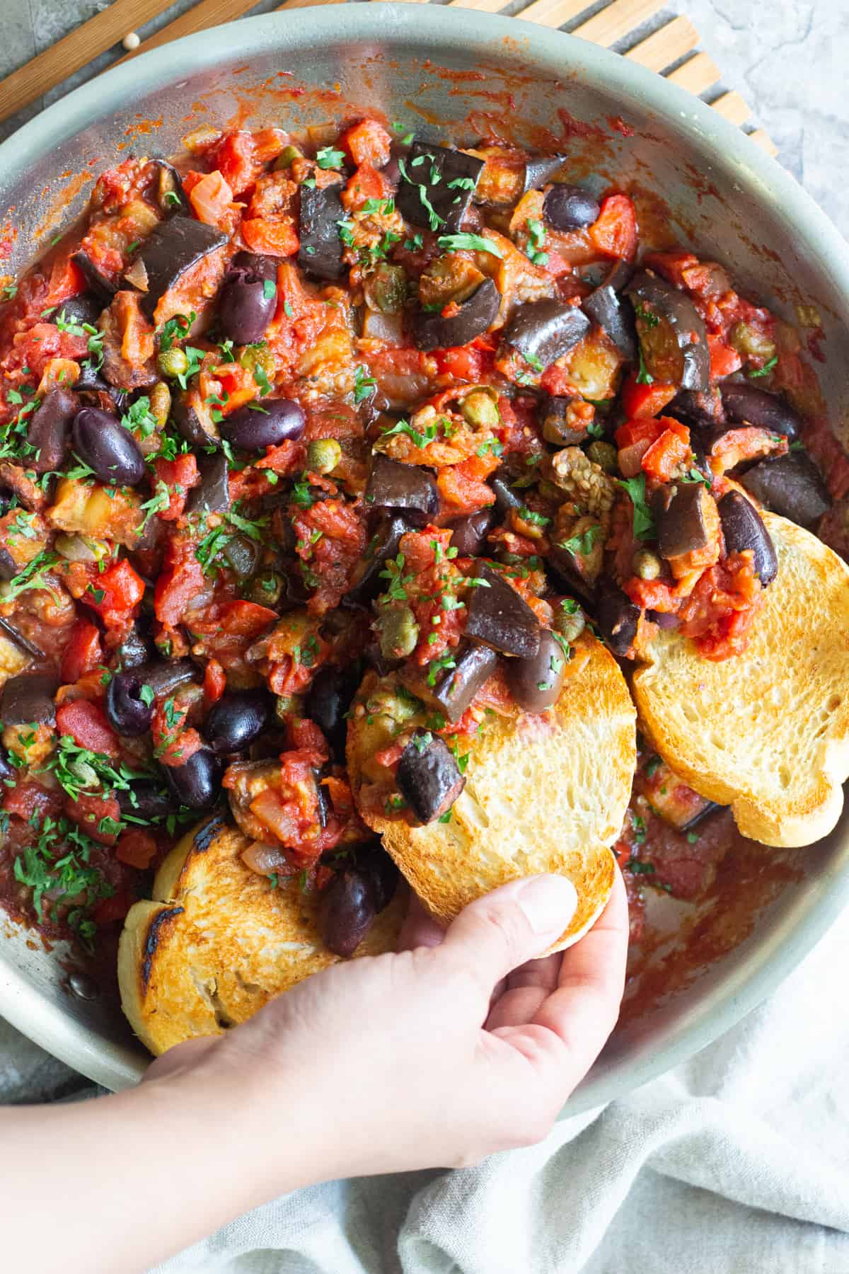 A pan of eggplant caponata with two slices of bread.
