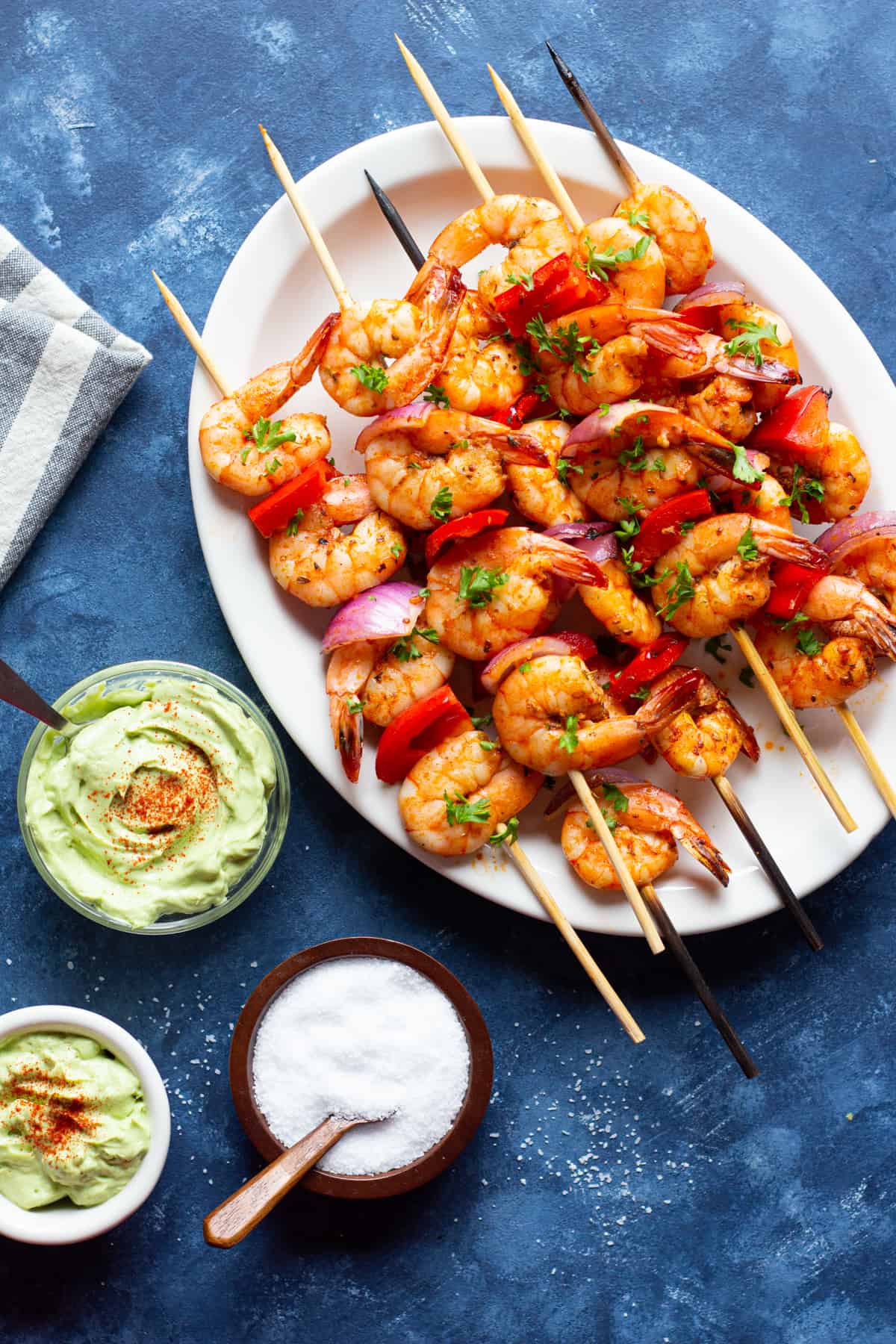 grilled shrimp skewers on a serving plate with creamy avocado sauce. 