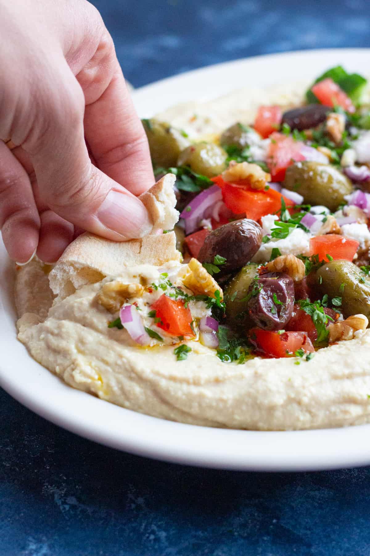 This loaded hummus recipe with all the fixings is ready in 15 minutes! Creamy hummus is topped with delicious toppings and served with pita!
