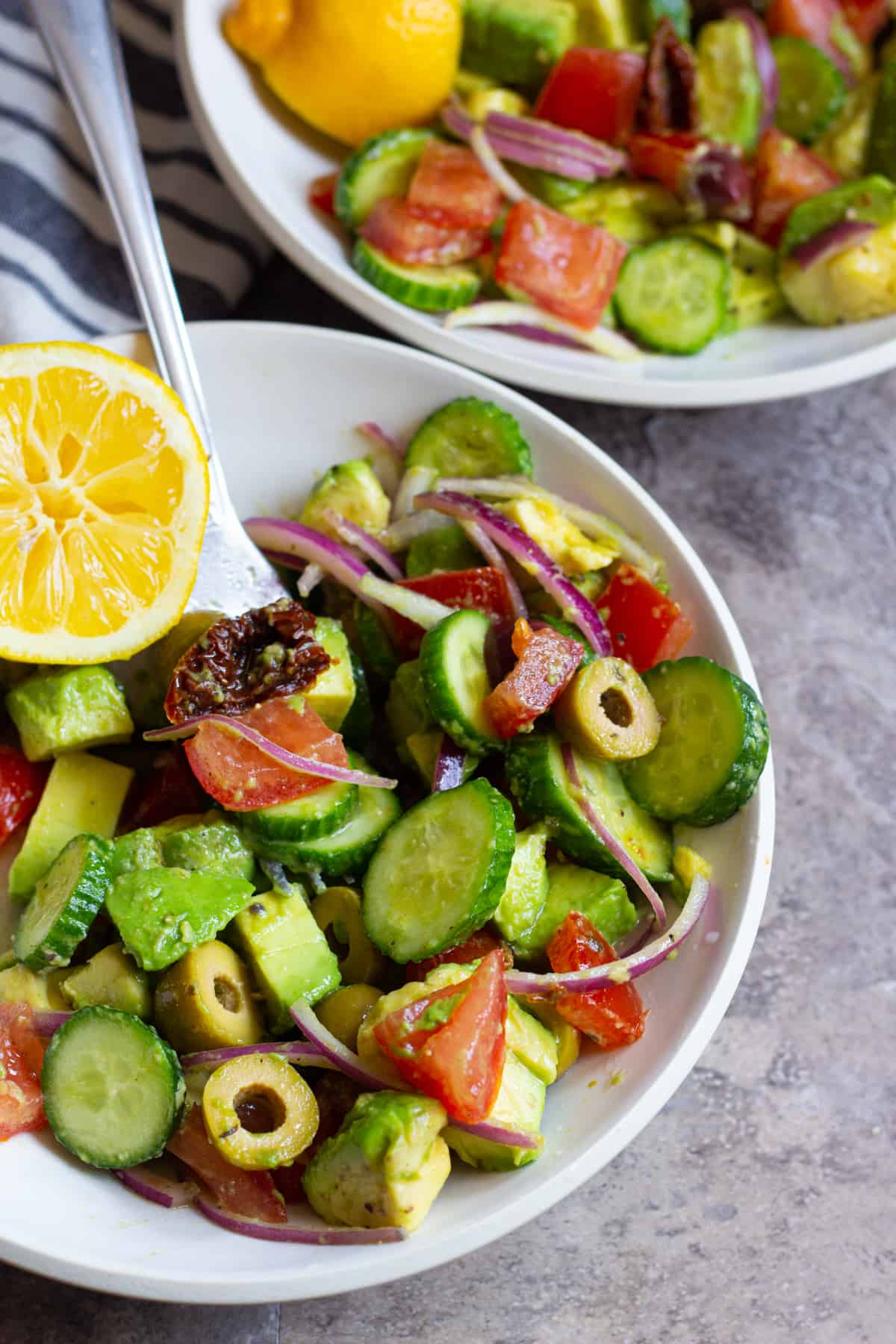 Serve avocado tomato salad in two smaller bowls with lemon.