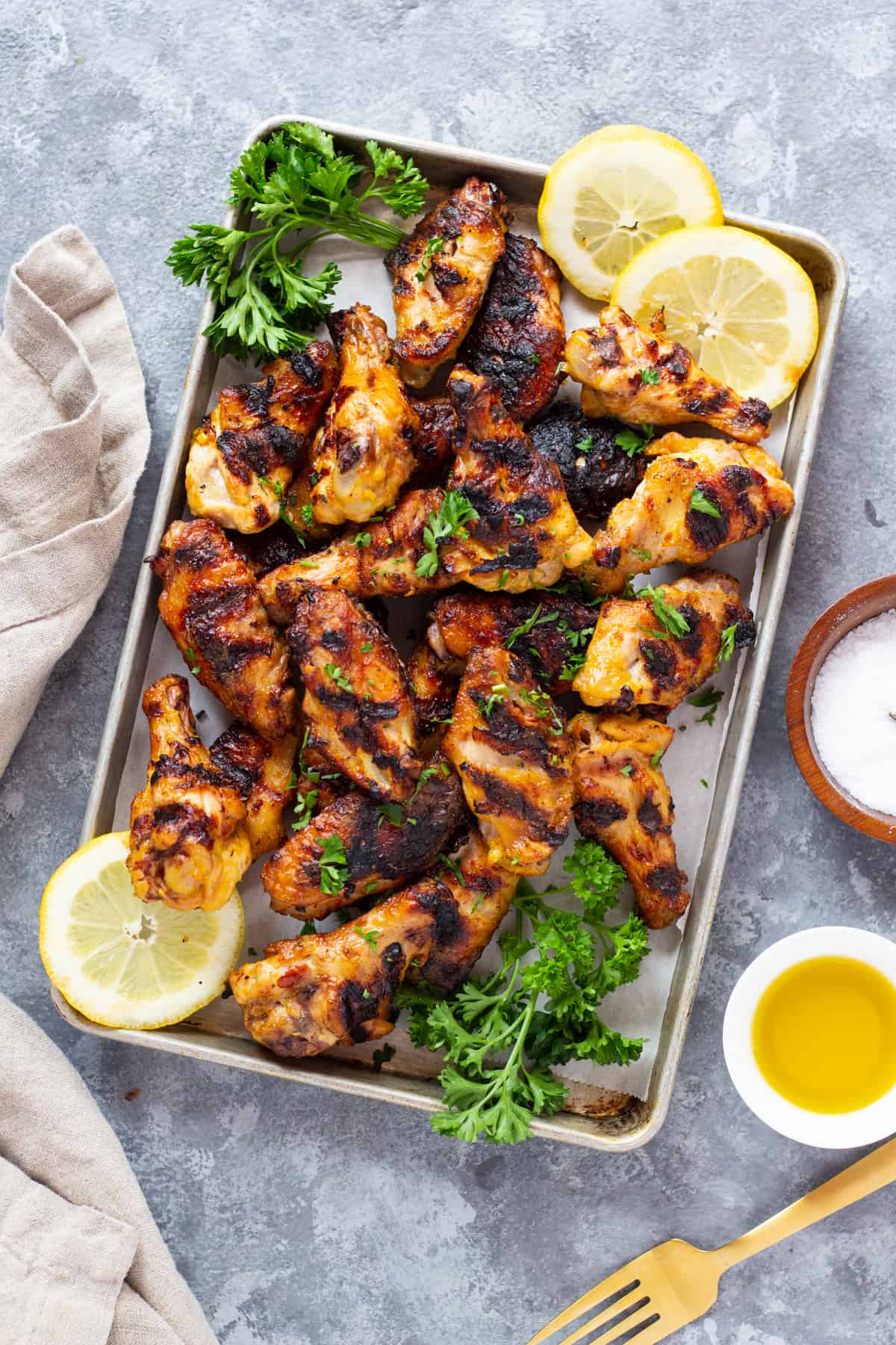 Chicken wings are grilled Persian style. Placed on a tray with sliced lemon and parsley. 