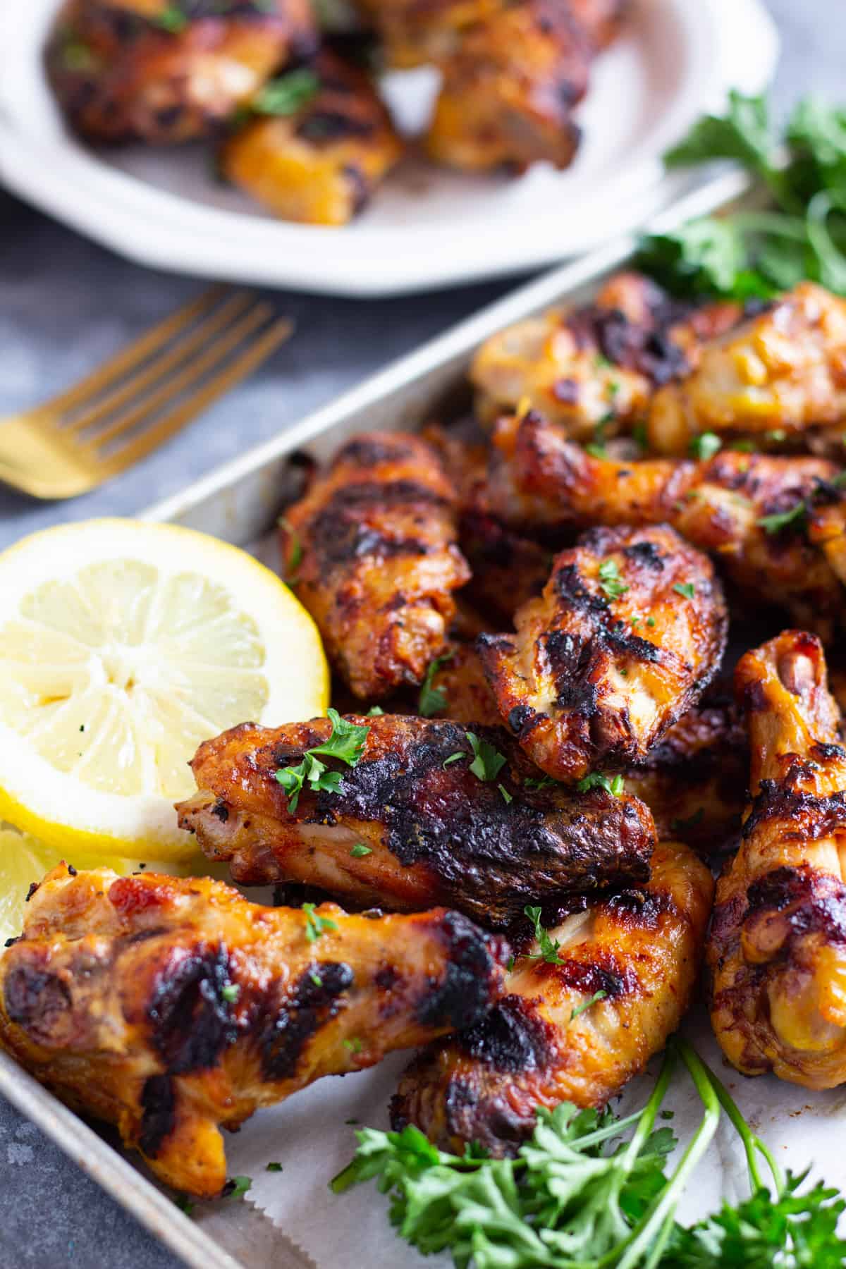 Persian style grilled wings on a tray with lemon and herbs. 