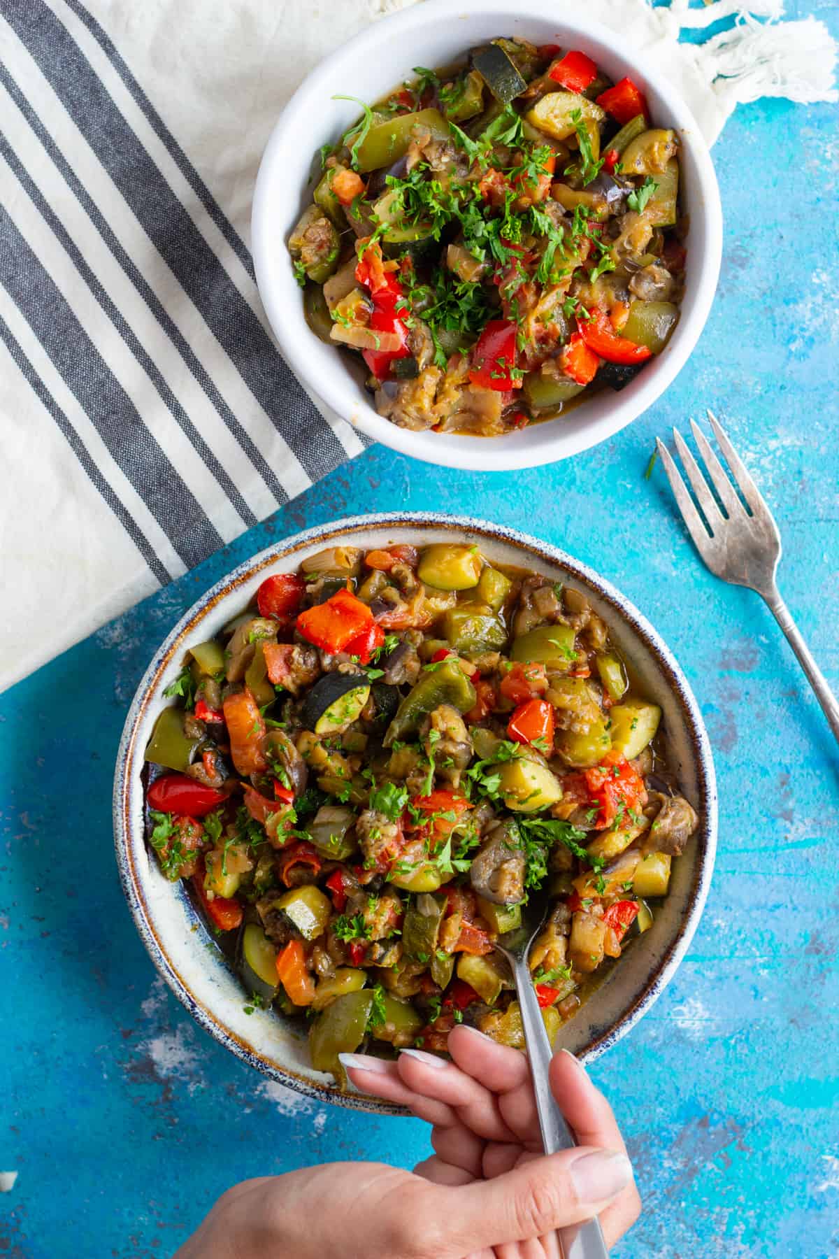 Two bowl of vegetable stew on the table and served with a fork.