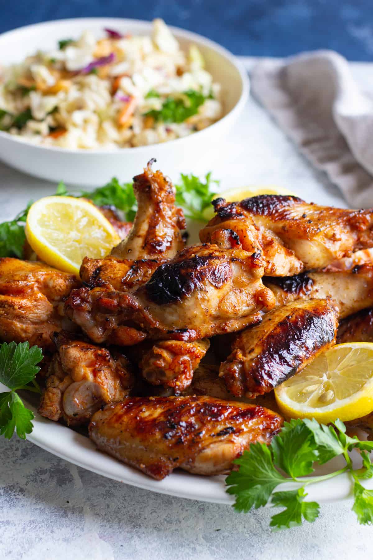 A plate of cooked chicken wings and a bowl of salad. 