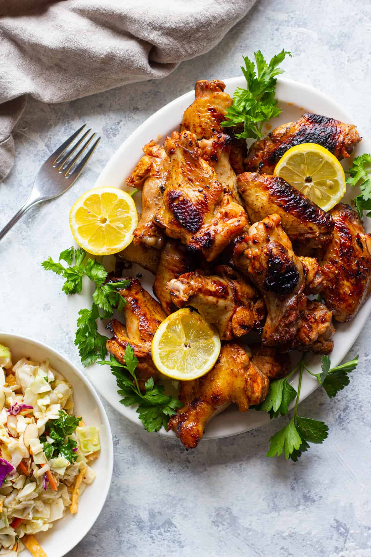 Overhead shot of chicken wings topped with lemon with a side salad.