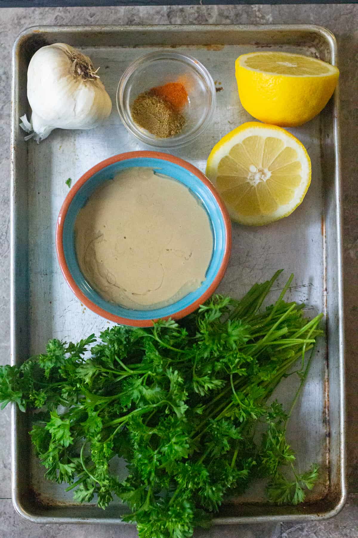 To make tahini dressing you need tahini, lemon, spices, garlic and parsley. 