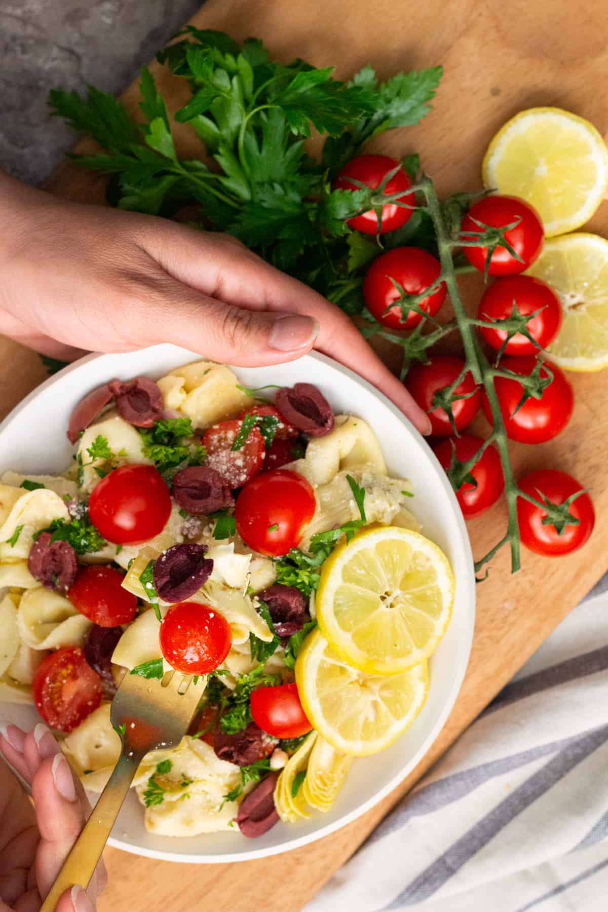 Tortellini pasta salad in a bowl held by hands. 