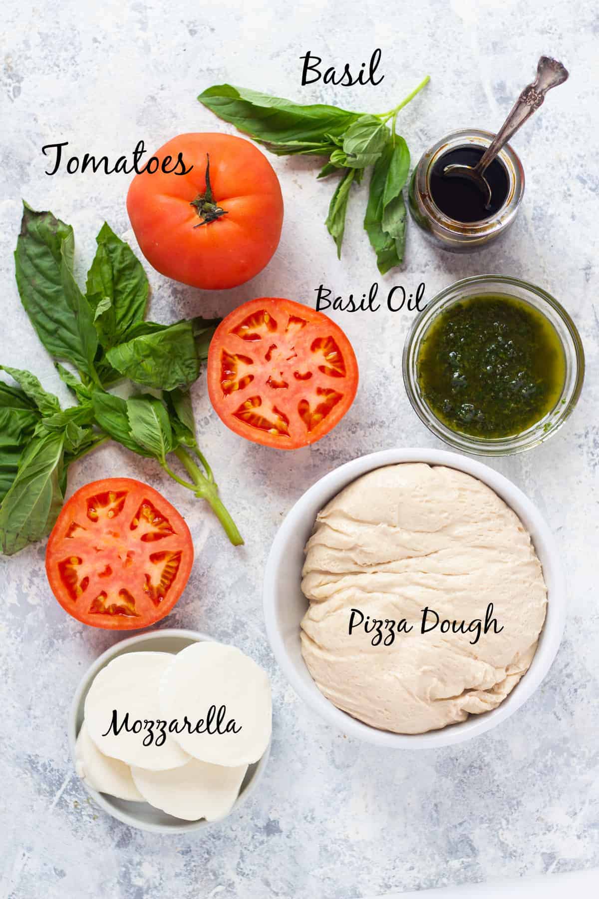 ingredient shot with pizza dough, basil, tomatoes and mozzarella. 