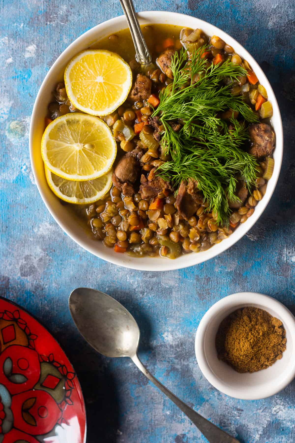 A bowl of chicken vegetable and lentil soup topped with lemon and dill. 