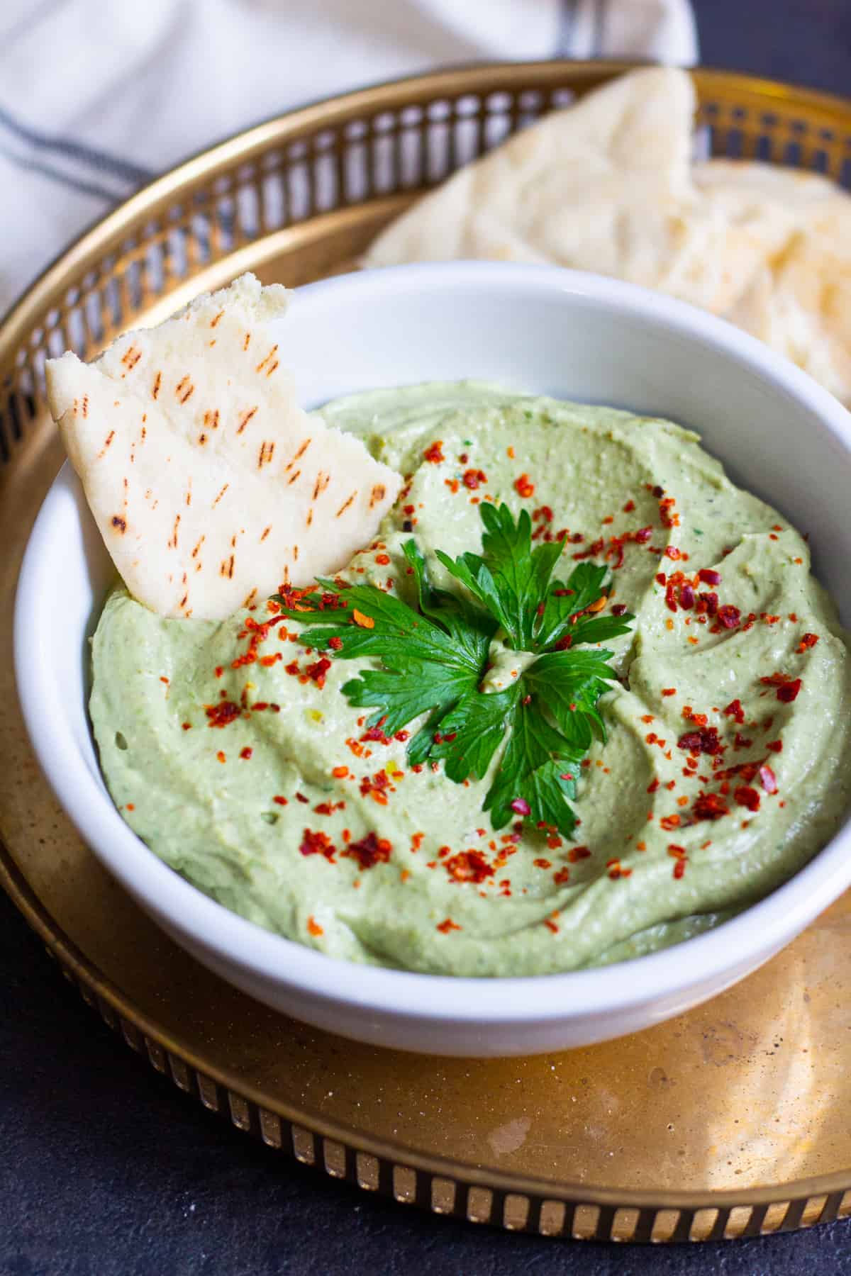 Top pistachio avocado dip with parsley and red pepper flakes. 