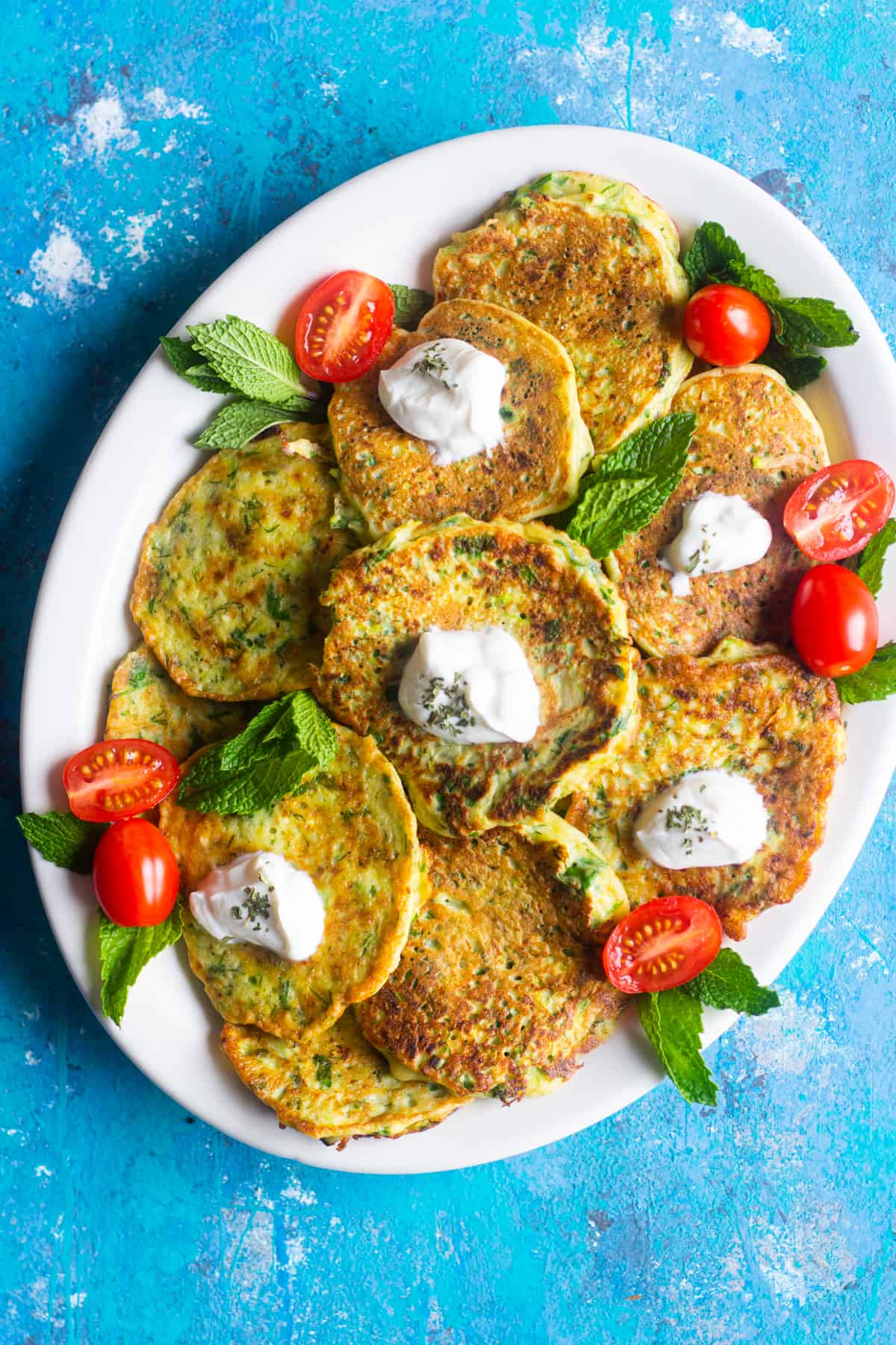 A plate of zucchini fritters topped with yogurt. 