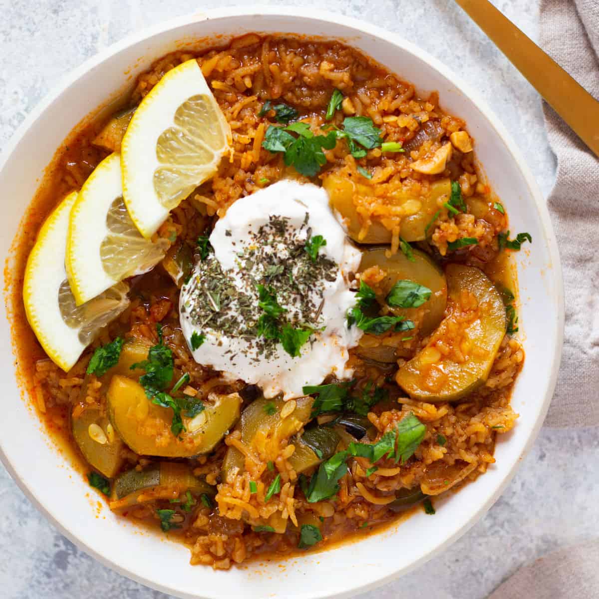 Turkish zucchini stew in a bowl topped with yogurt and dried mint. 