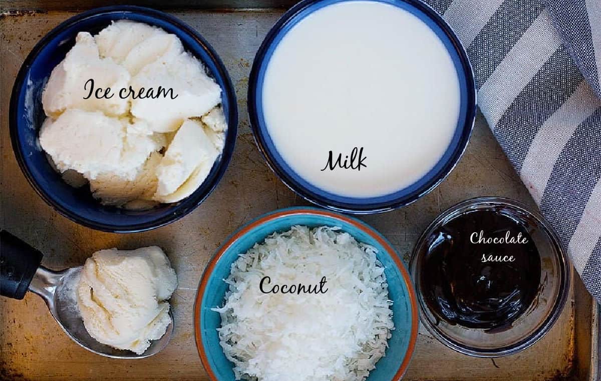 Coconut milkshake ingredients are vanilla ice cream, coconut milk, chocolate sauce and shredded coconut.