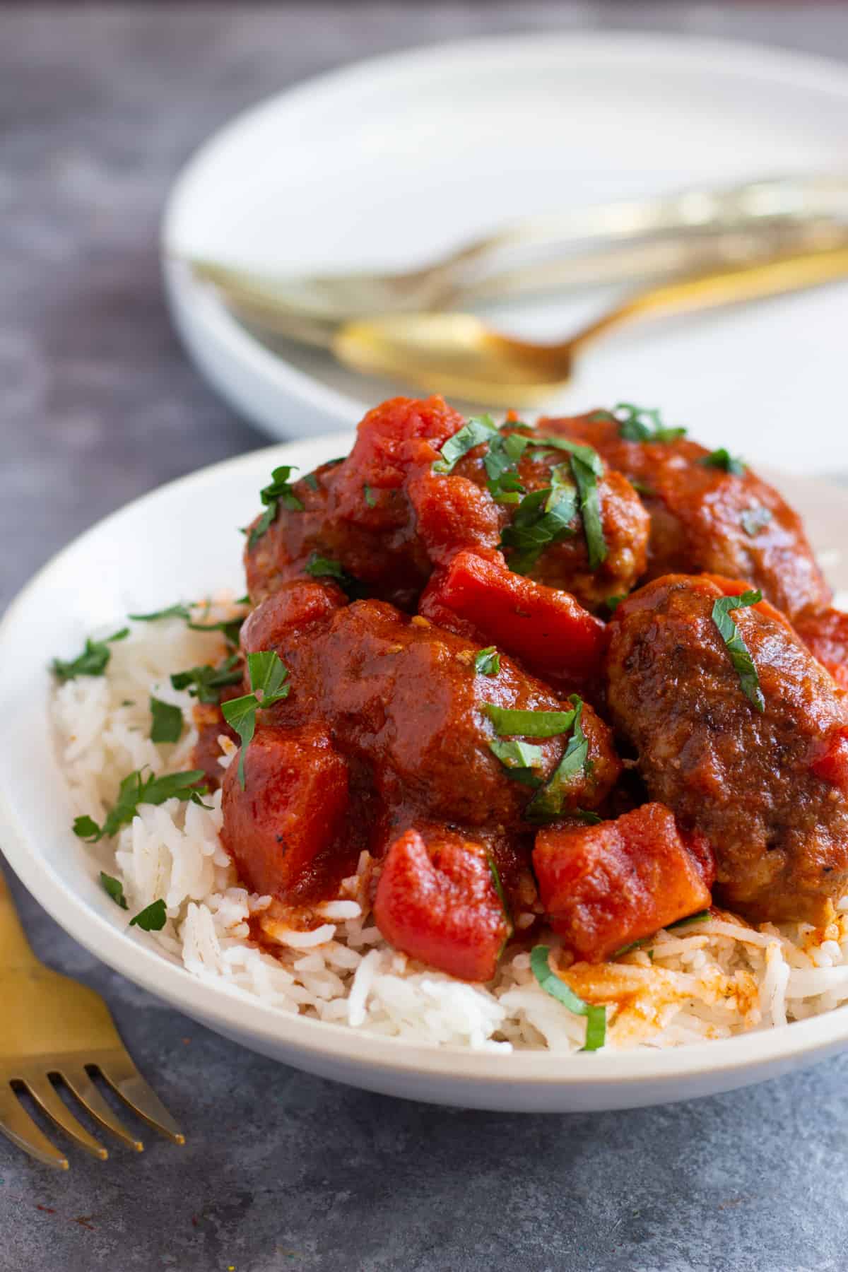 Soutzoukakia are Greek style meatballs cooked in a delicious tomato sauce. These meatballs are juicy thanks to a simple technique and are perfect with some rice, potatoes or even pasta. Learn how to make juicy meatballs every time with my simple method! This is a super easy dinner recipe that everyone loves!