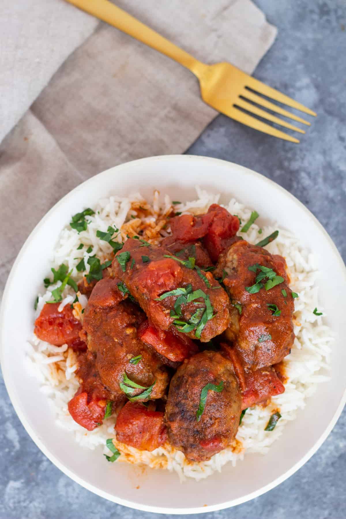 Overhead shot of Greek baked meatballs in tomato sauce with rice. 