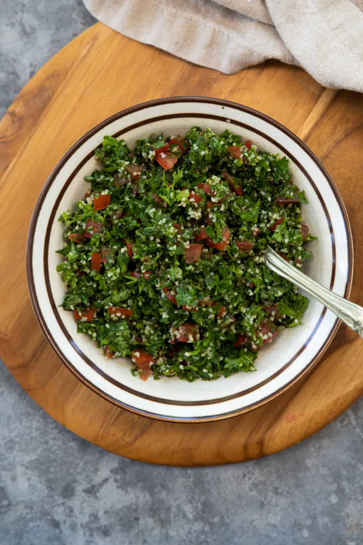 a bowl of tabbouleh salad on a wooden board. 