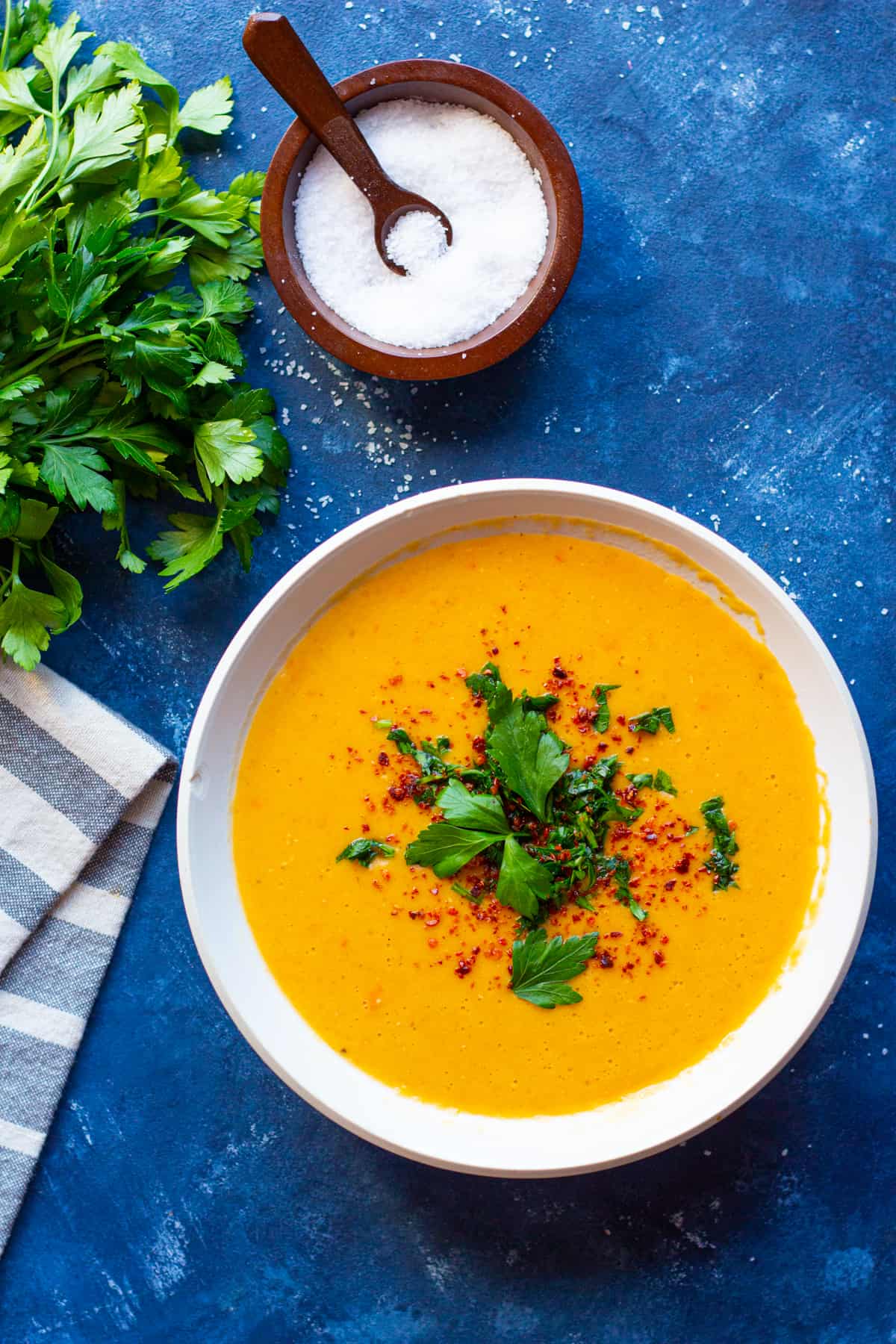 A bowl of soup topped with pepper and parsley. 