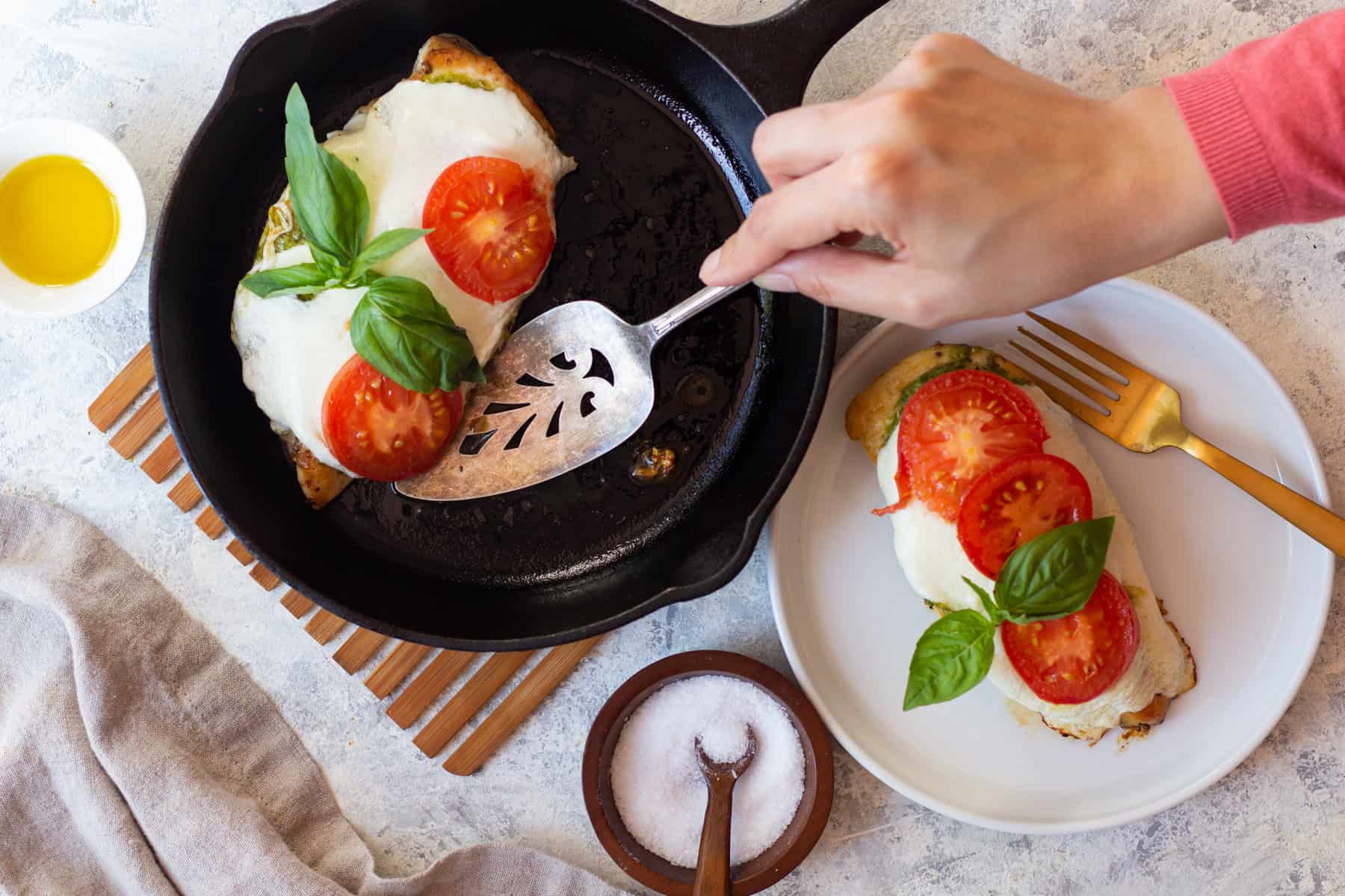 A pan of chicken caprese and a plate with pesto caprese chicken in it. 