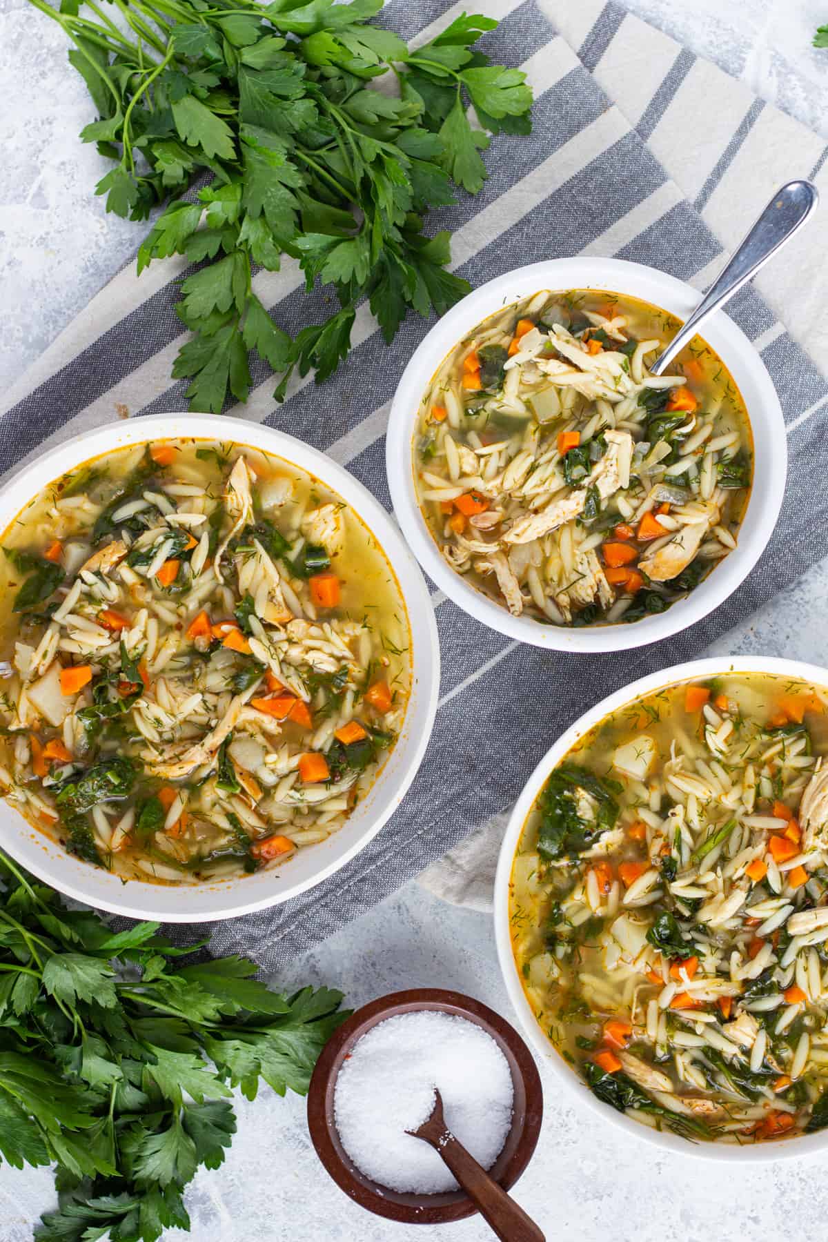 Three white bowls of soup. This is the chicken soup made with orzo and spinach. 