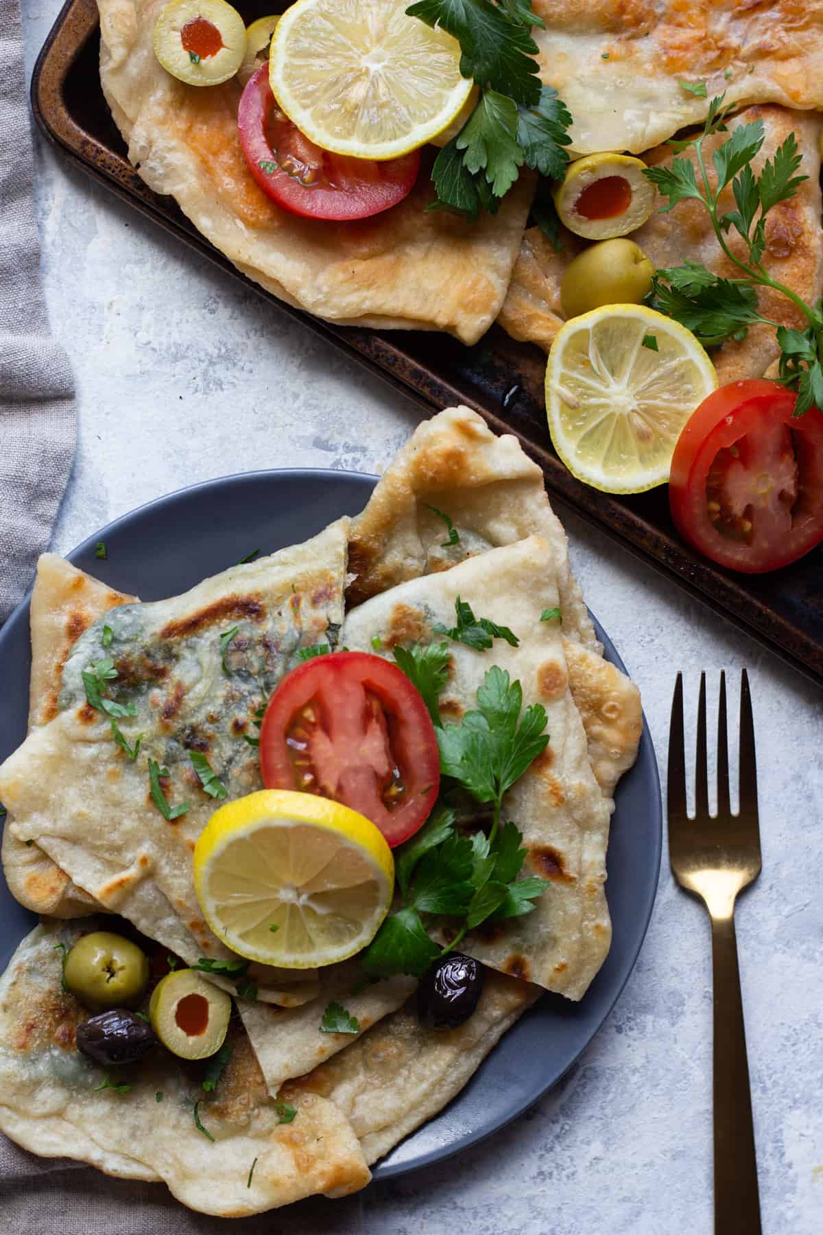 A plate of traditional gozleme served with lemon, tomatoes and olives. 