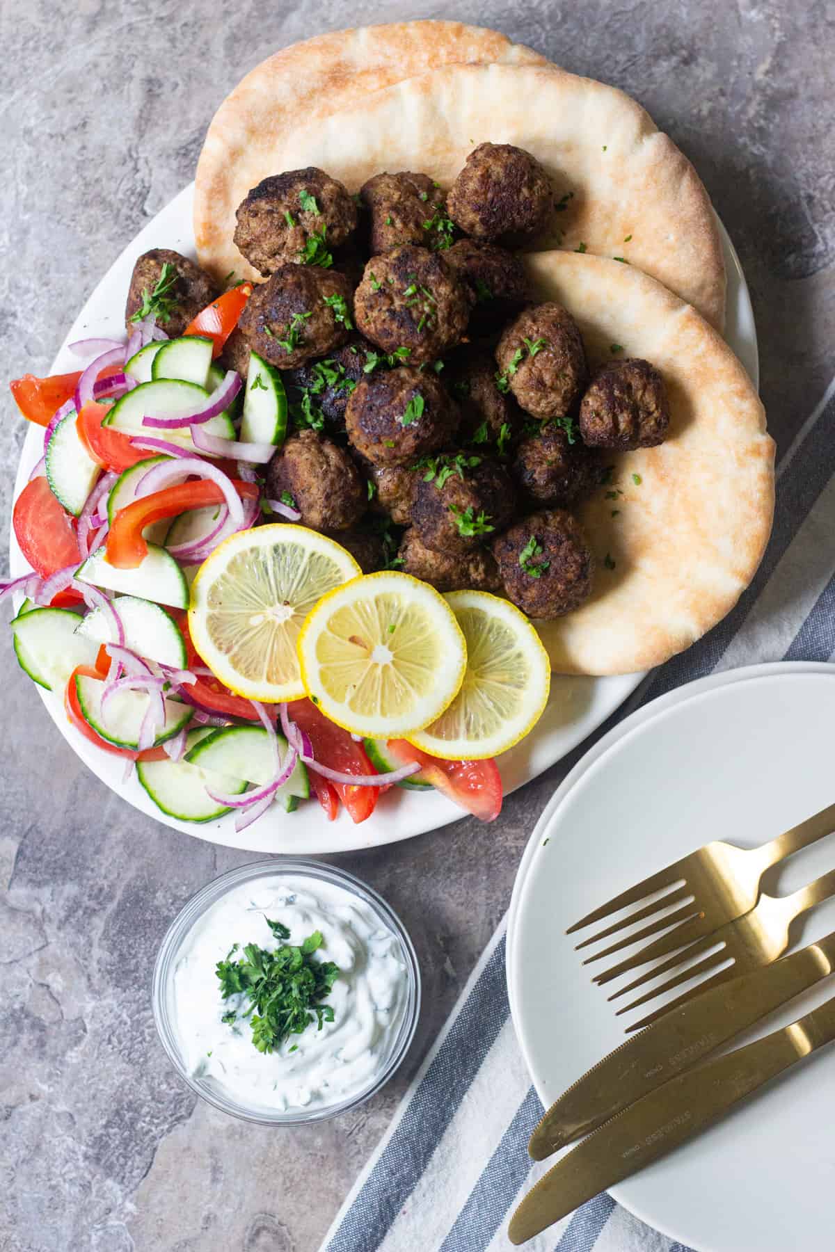 Serve Greek lamb meatballs with pitas and vegetables.