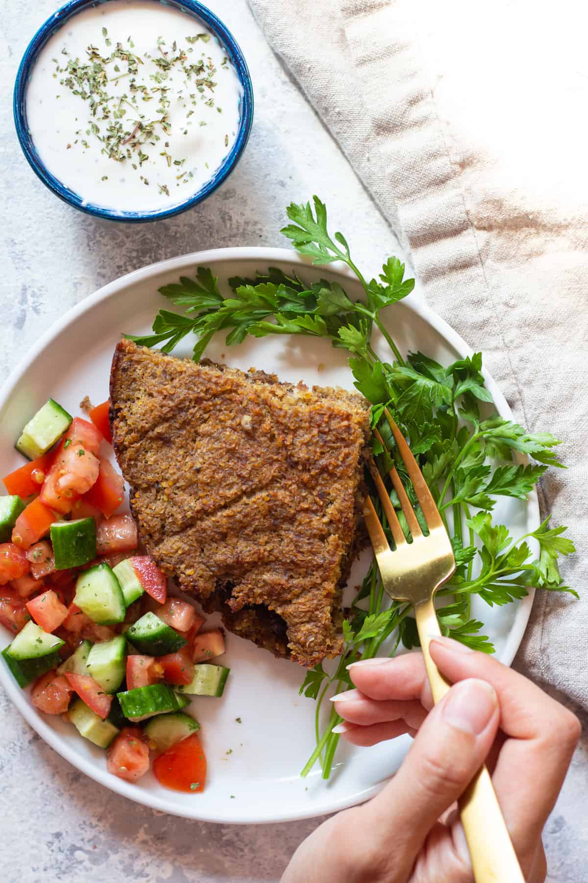 a plate of baked kibbeh with yogurt sauce. 