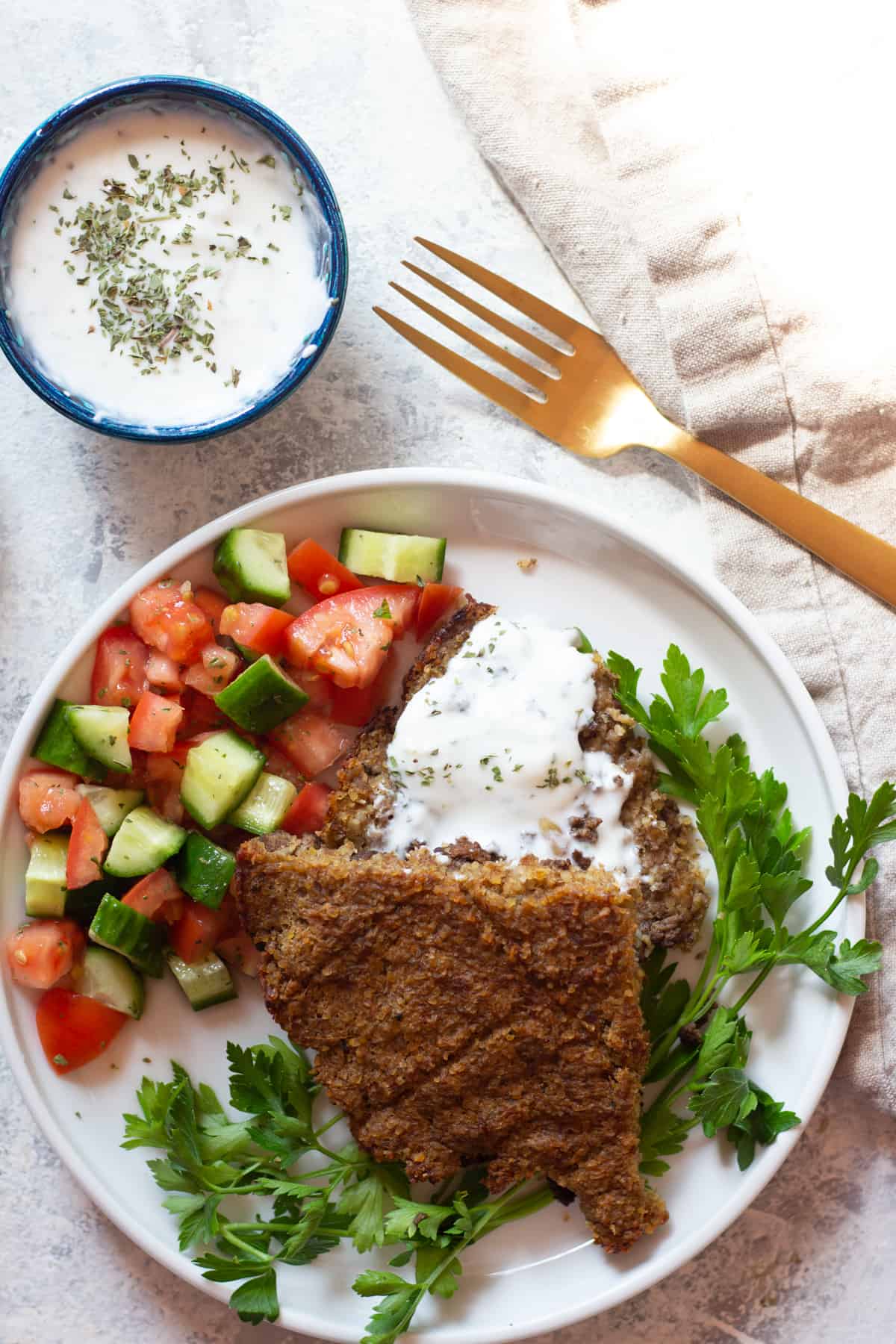 Baked middle eastern kibbeh with tomato cucumber salad and yogurt sauce. 