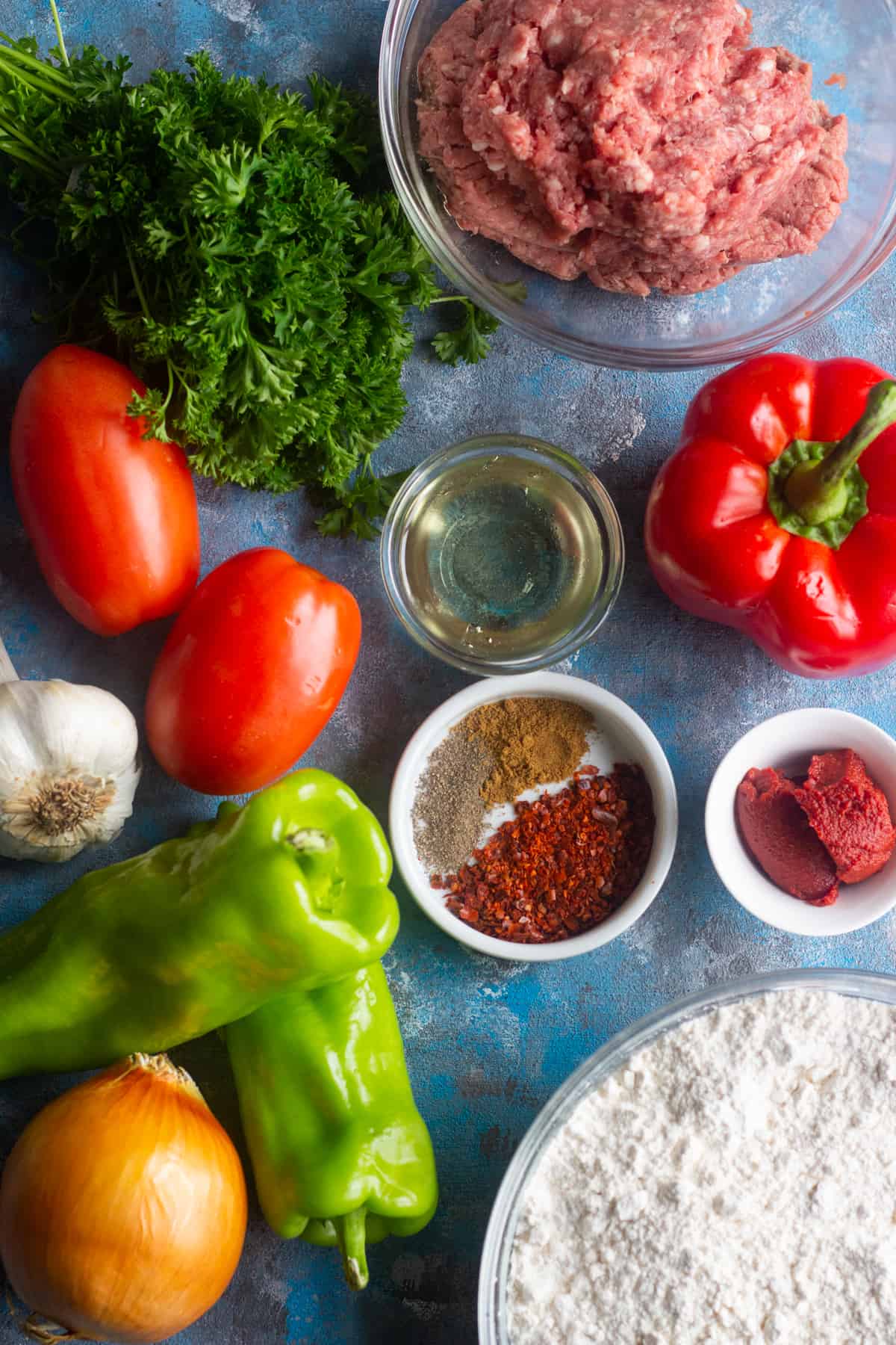To make Lahmacun Turkish Pizza you need a dough and ground lamb or beef (or a combination of both), tomatoes, onions, garlic, parsley, red bell peppers and Italian green peppers. This mixture is seasoned with Aleppo pepper, tomato paste, black pepper and salt. 