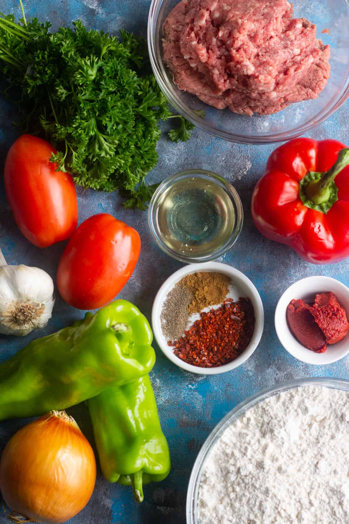 To make Lahmacun Turkish Pizza you need a dough and ground lamb or beef (or a combination of both), tomatoes, onions, garlic, parsley, red bell peppers and Italian green peppers. This mixture is seasoned with Aleppo pepper, tomato paste, black pepper and salt.