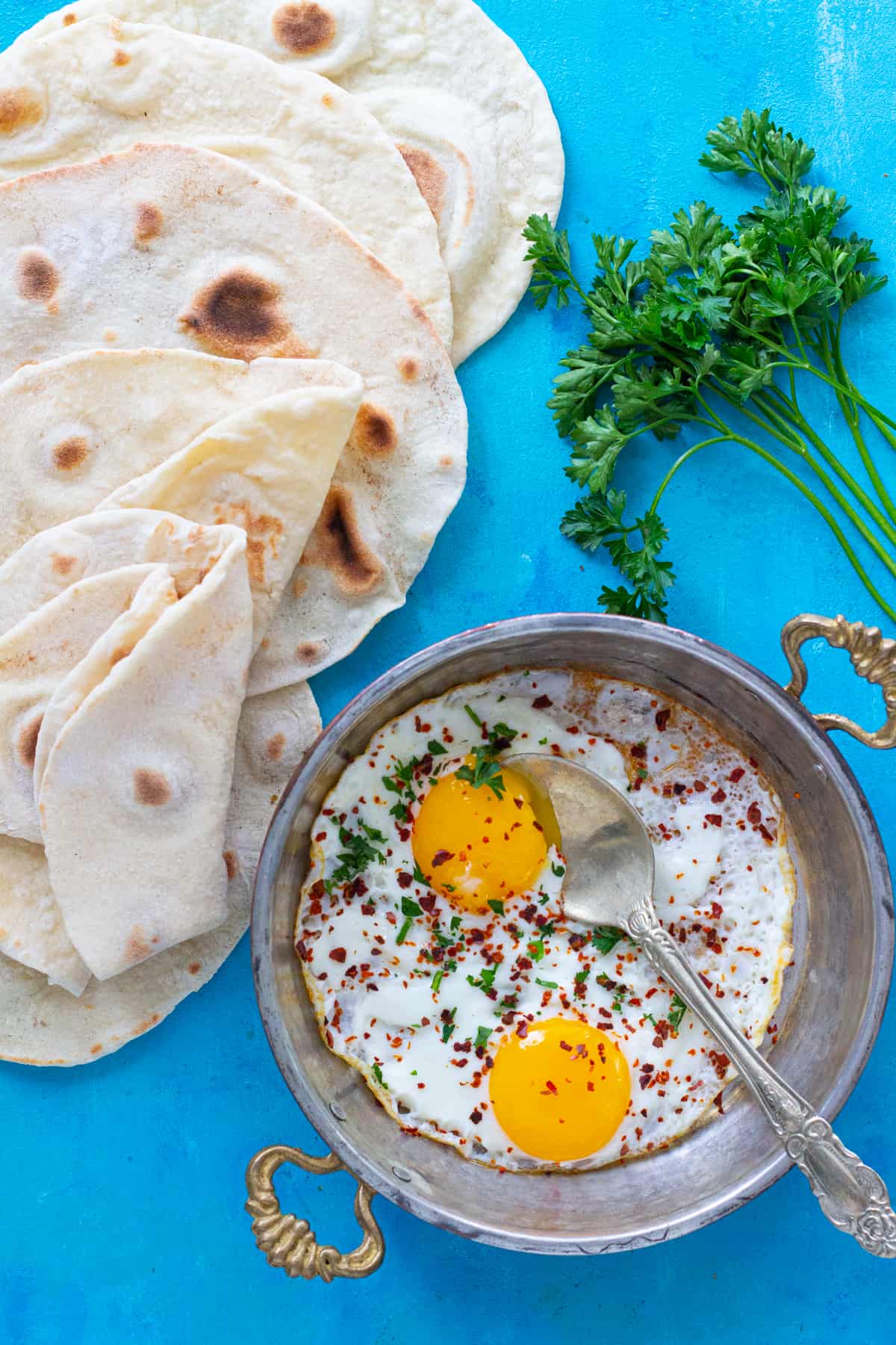 A pan of fried eggs and homemade lavash bread. 
