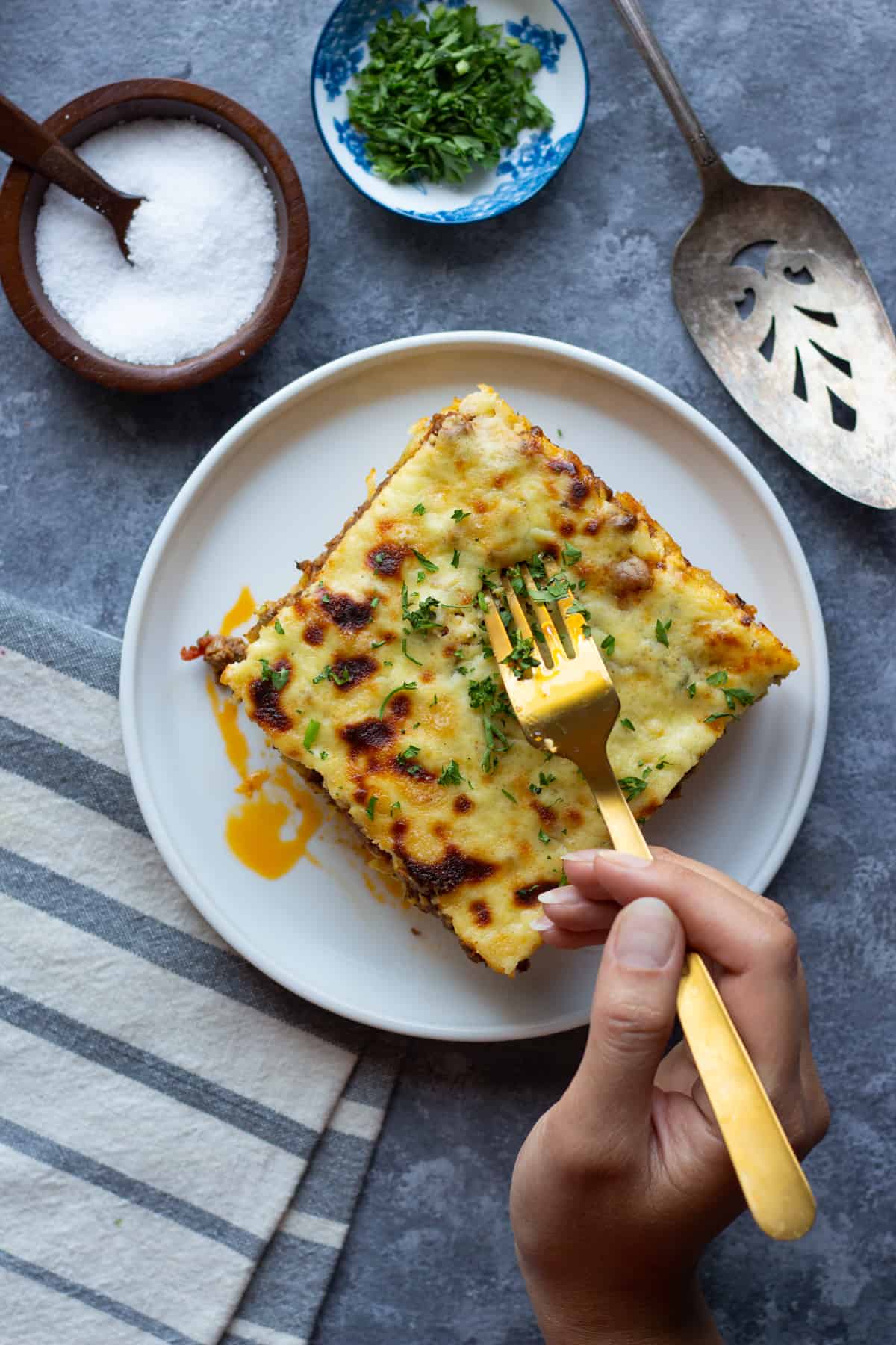 Pastitsio is also known as Greek lasagna A slice of it is topped with chopped parsley.