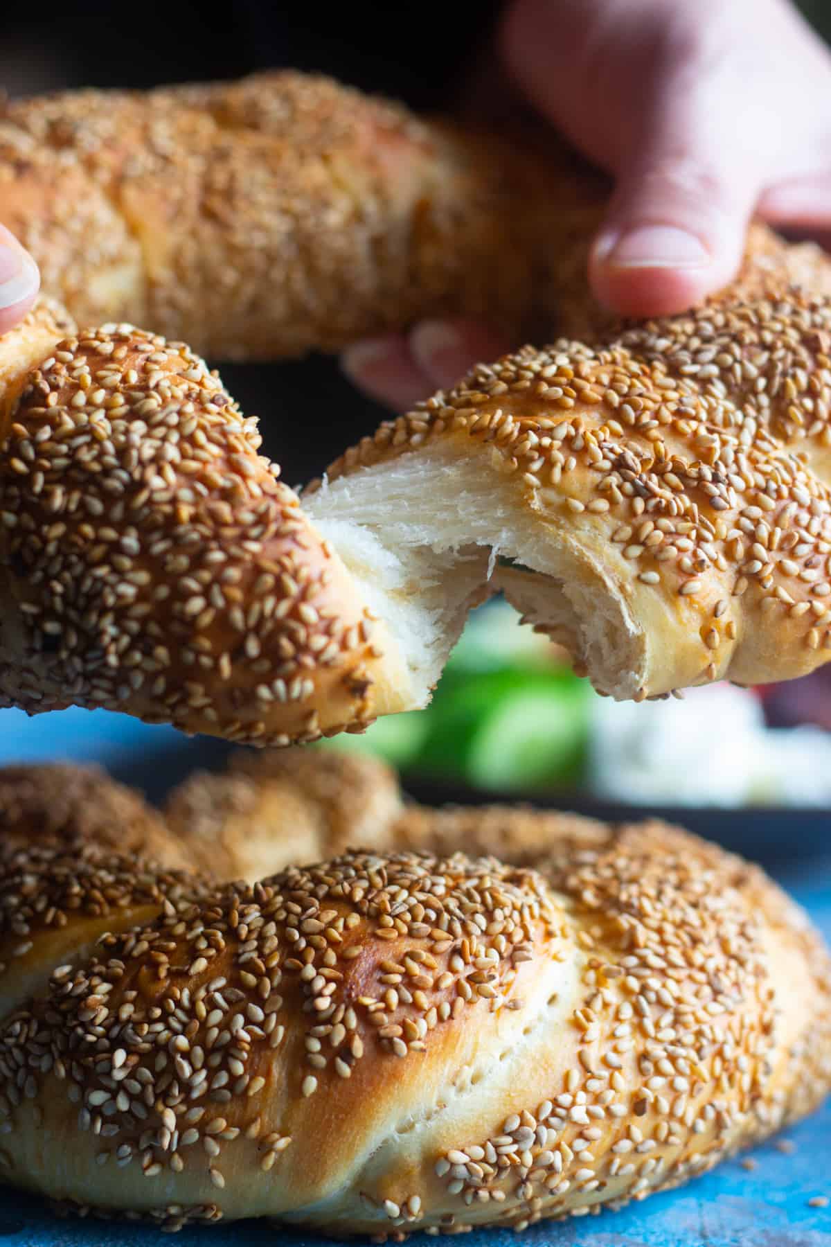 A piece of simit being torn with hands,