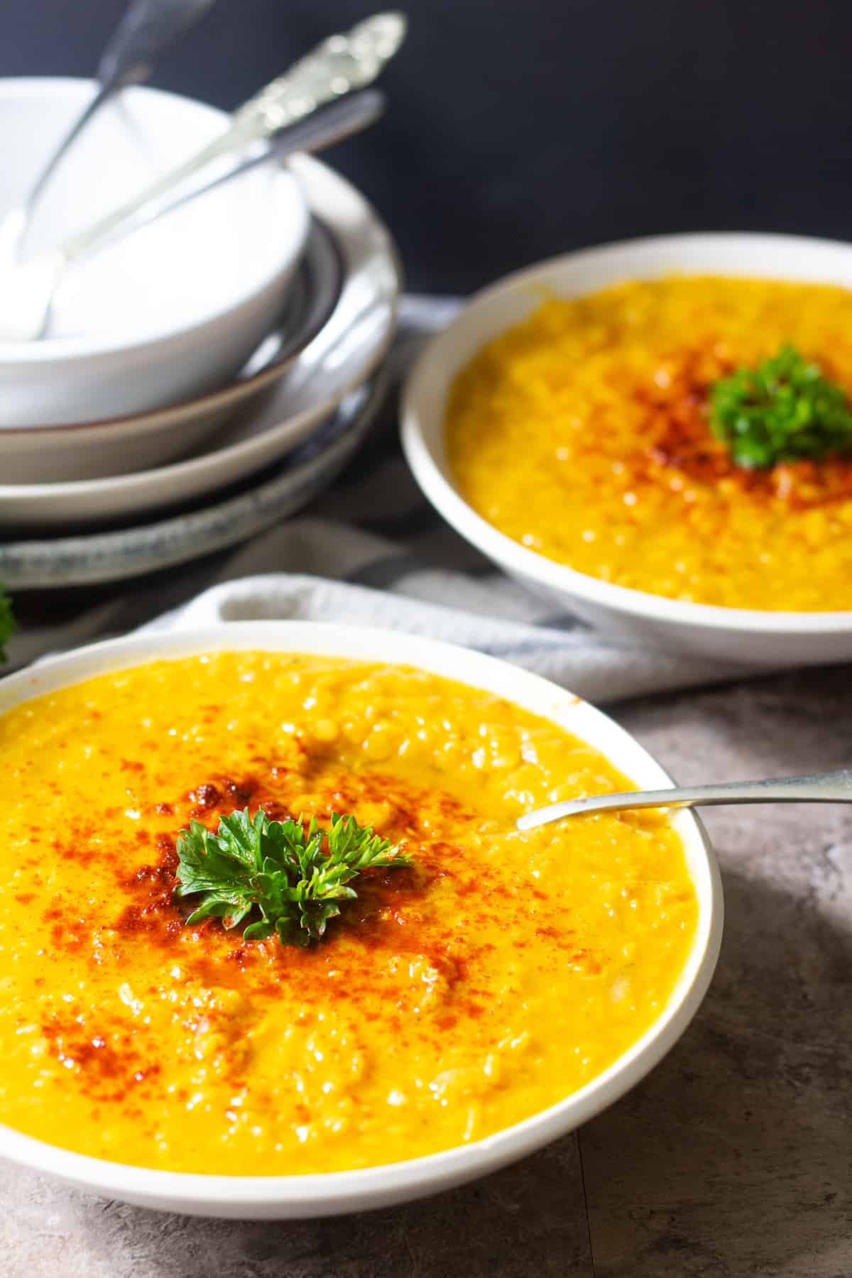 close up shot red lentil soup topped with red pepper. 