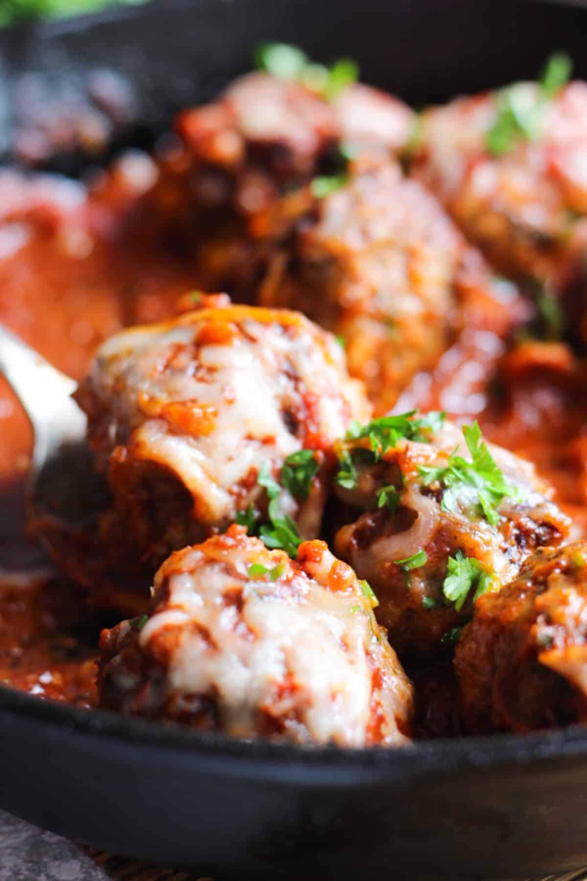 Meatballs topped with cheese and parsley. 