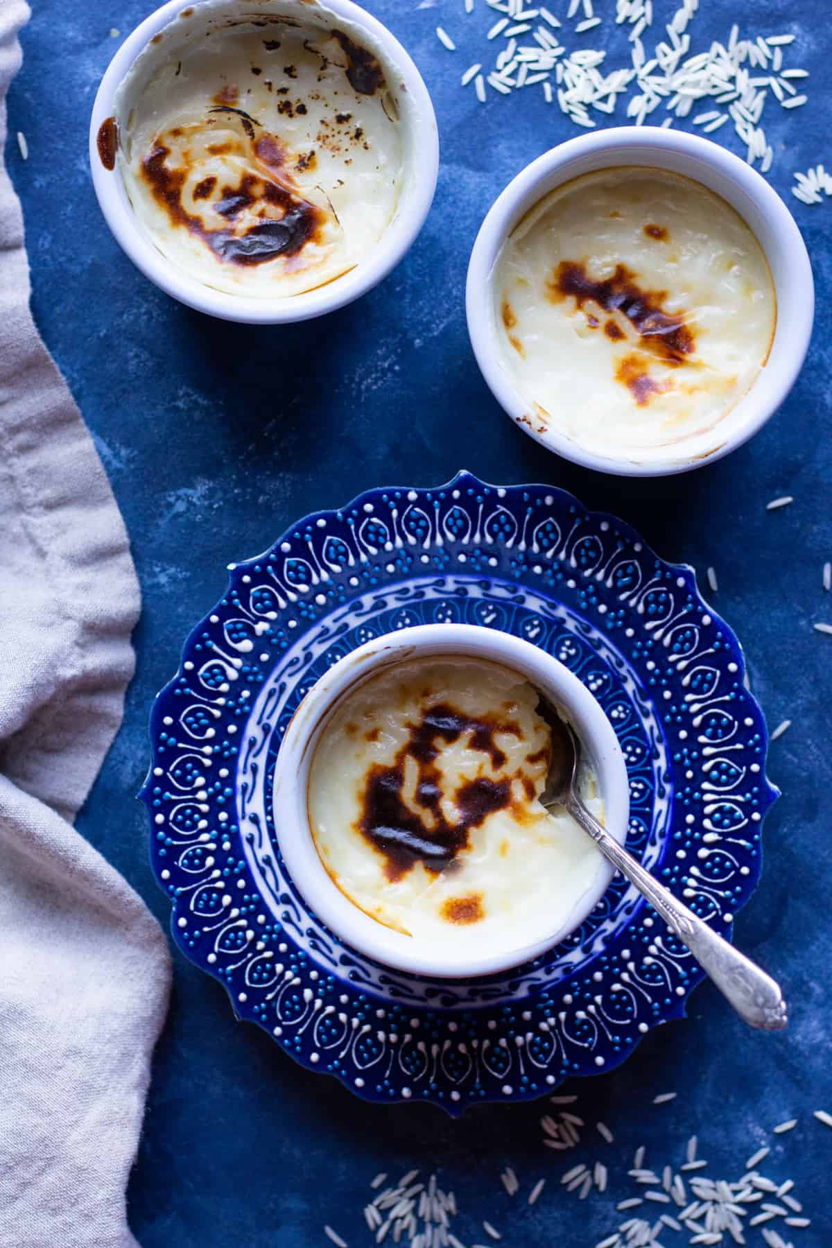 Baked rice pudding made in individual ramekins on a navy blue background. 