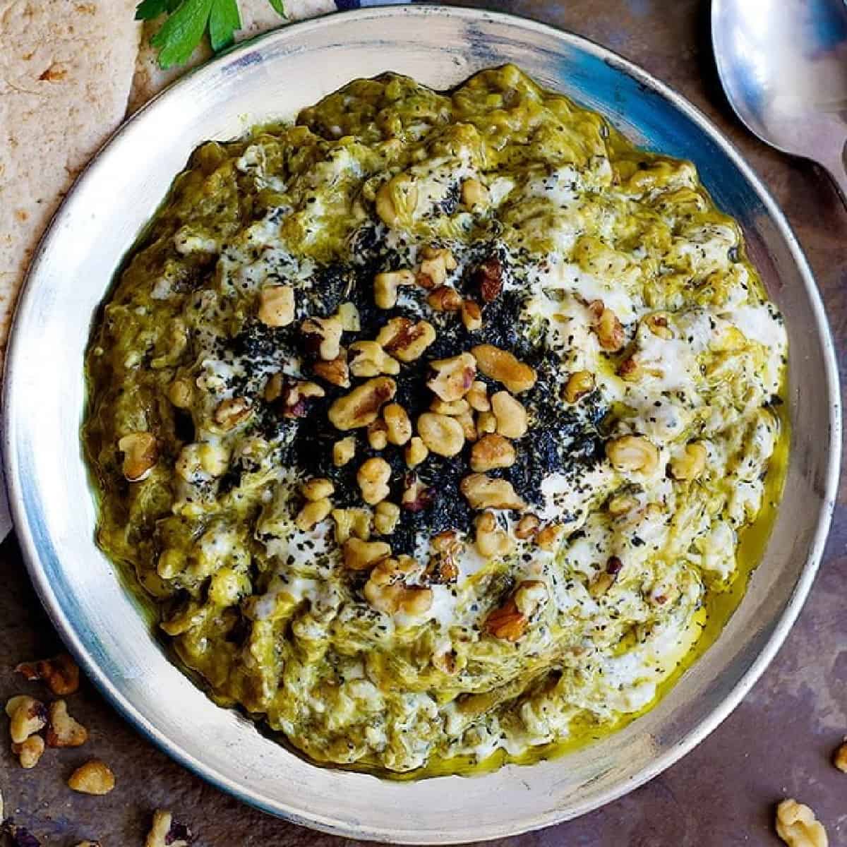 kashke bademjan Persian eggplant dip on a plate topped with dried mint and walnuts.