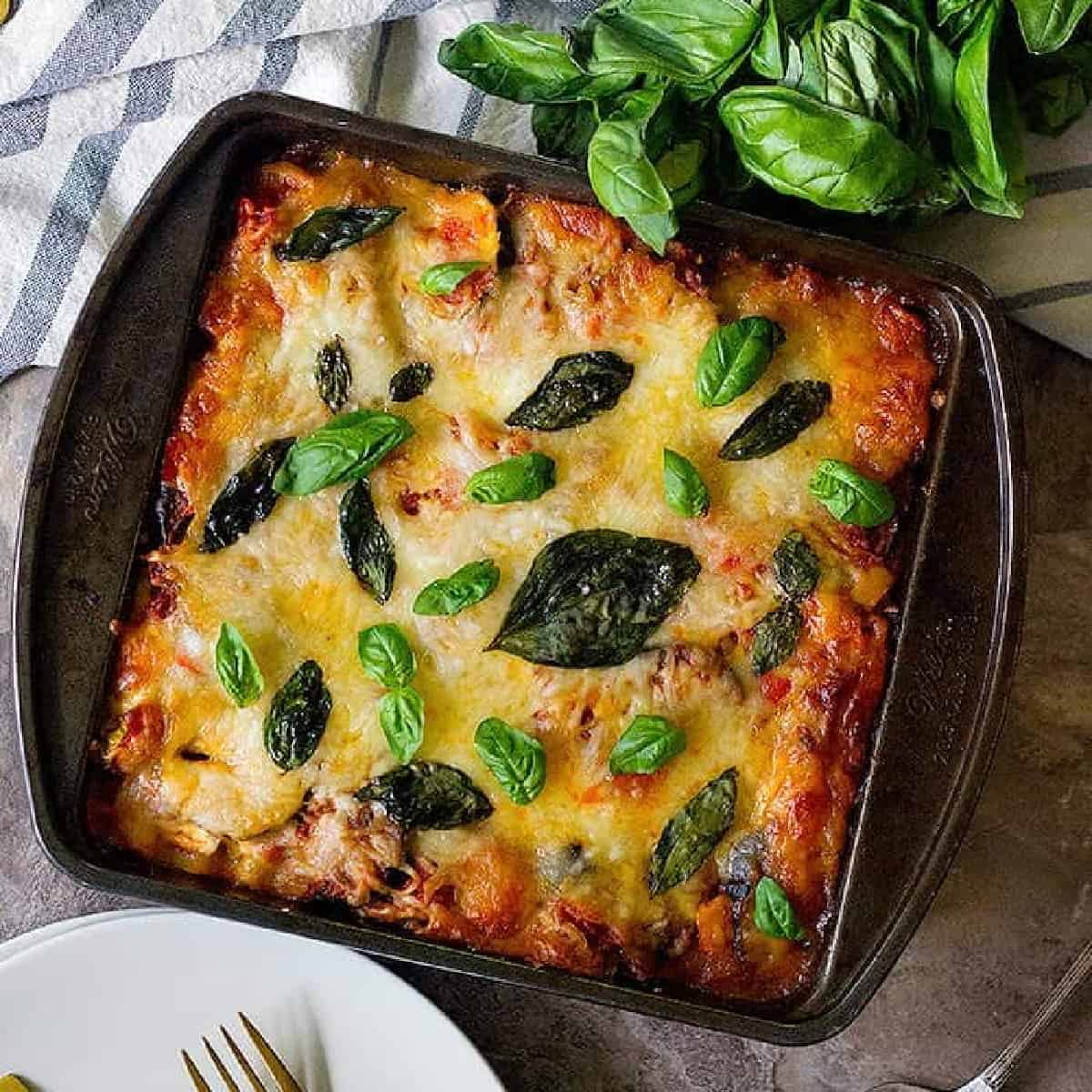 vegetable lasagna with basil in a pan on a backdrop. 
